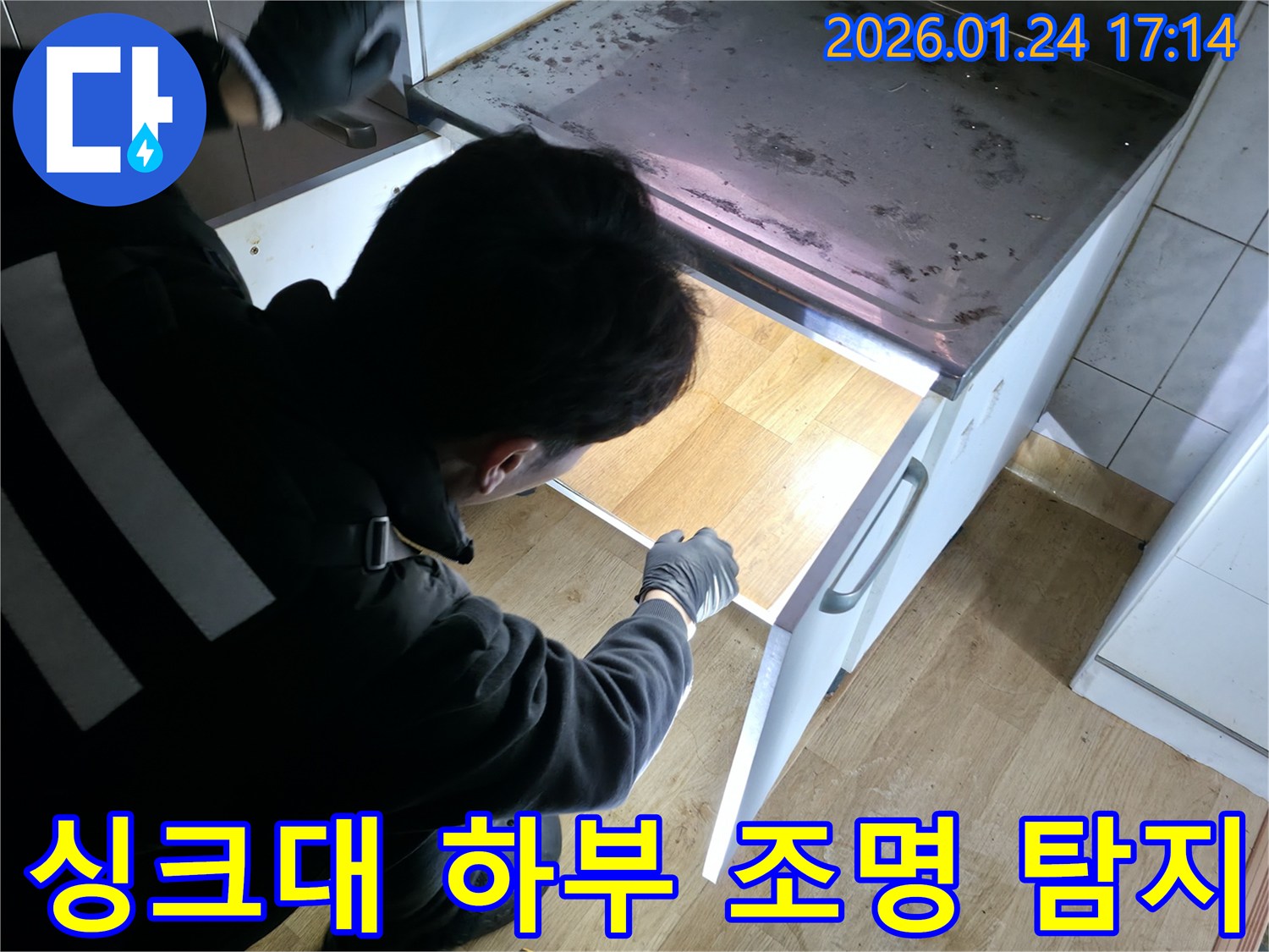 강북구 누수 전문가가 싱크대 하부의 어두운 곳을 조명으로 비춰가며 누수를 탐지하고 있습니다 - 숨겨진 누수도 놓치지 않습니다.