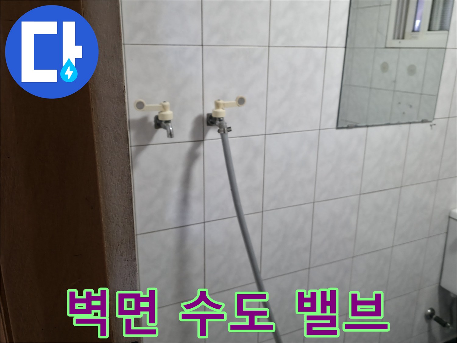 타일로 마감된-벽면에 노출된 수도 연결 부위입니다.