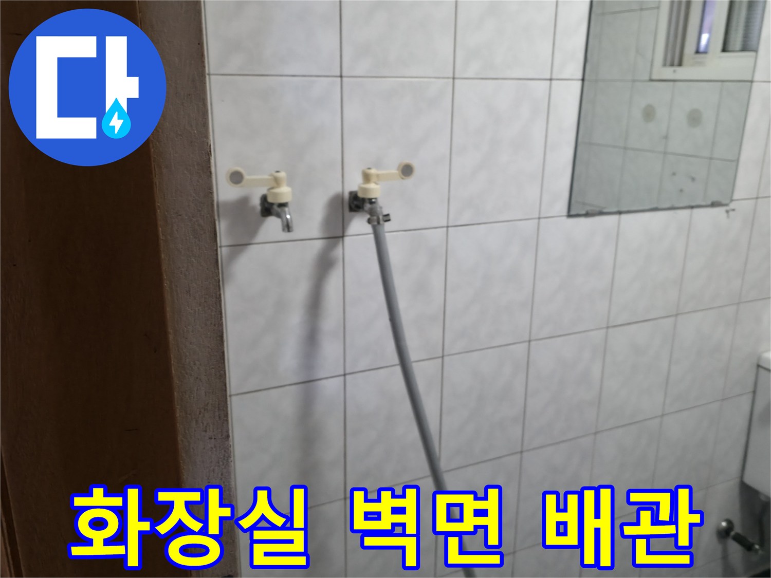 흰색 타일 벽면에 설치된 수도꼭지와 연결 호스 모습