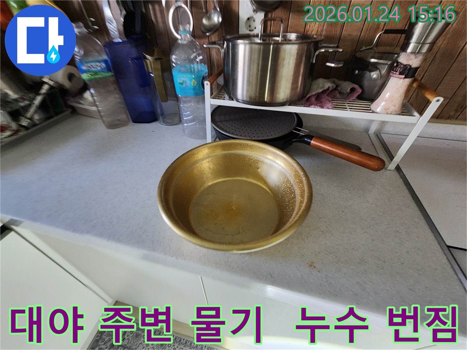 대야 주변 싱크대 상판에 보이는 물기 - 누수가 주변으로 번지고 있음을 나타냅니다.