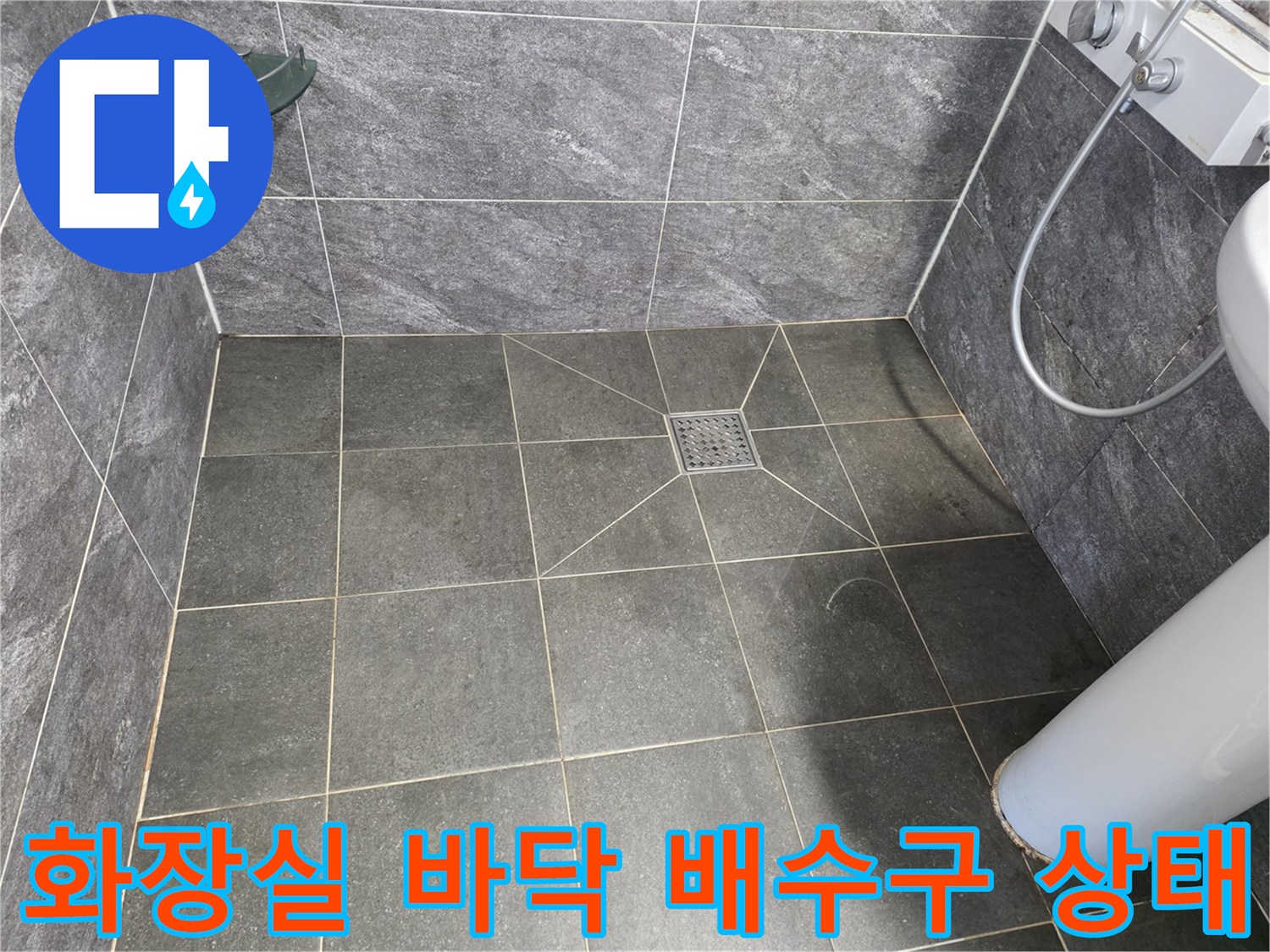 어두운 회색 타일과 중앙의 사각형 배수구 드레인 부위