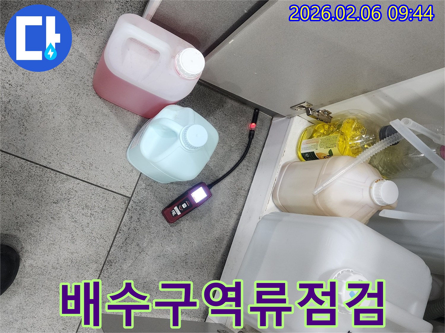 상가 주방 싱크대 아래에서 누수탐지 장비가 배수구 역류로 인한 누수 여부를 정밀하게 점검하고 있습니다