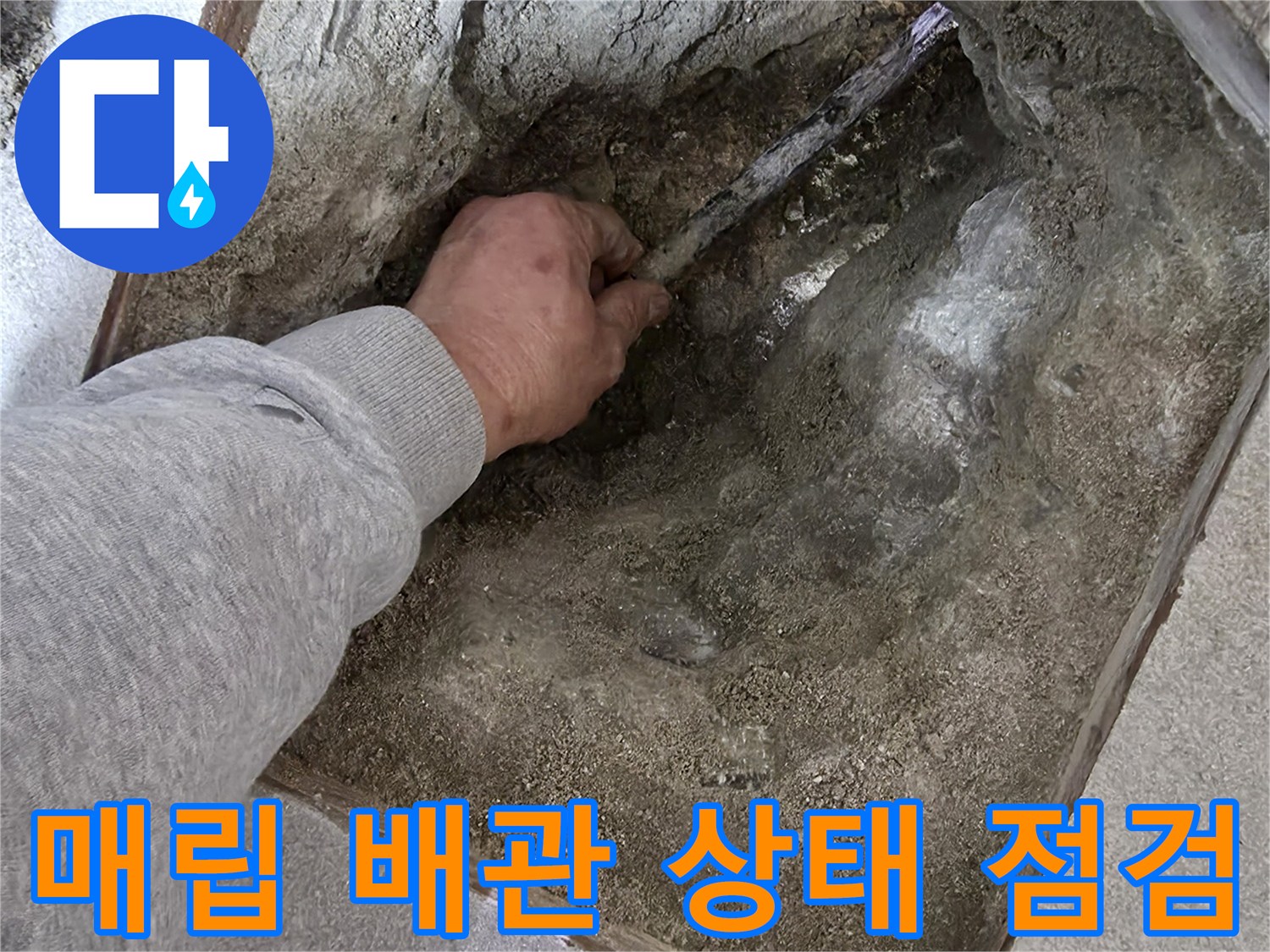 바닥 굴착 부위-노출된 배관 주변의 젖은 흙과 시멘트 상태를 확인하는 엔지니어