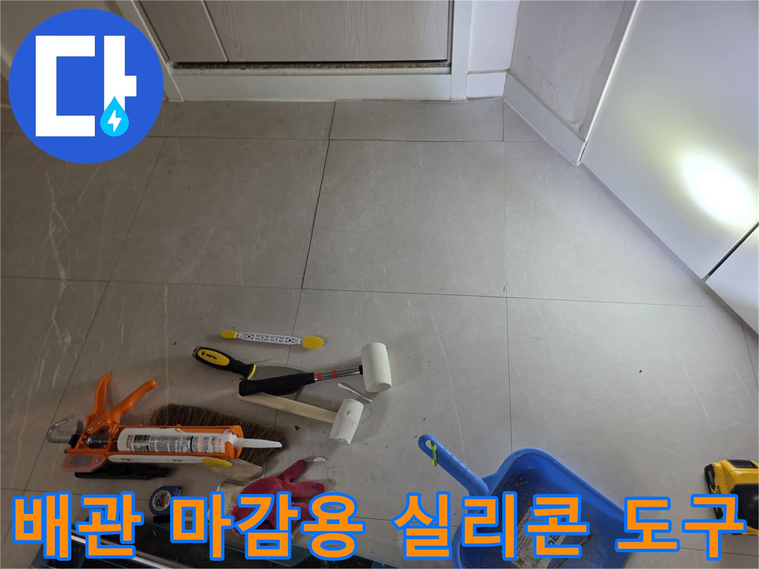 타일 바닥에 놓인 작업용 실리콘 건과 헤라