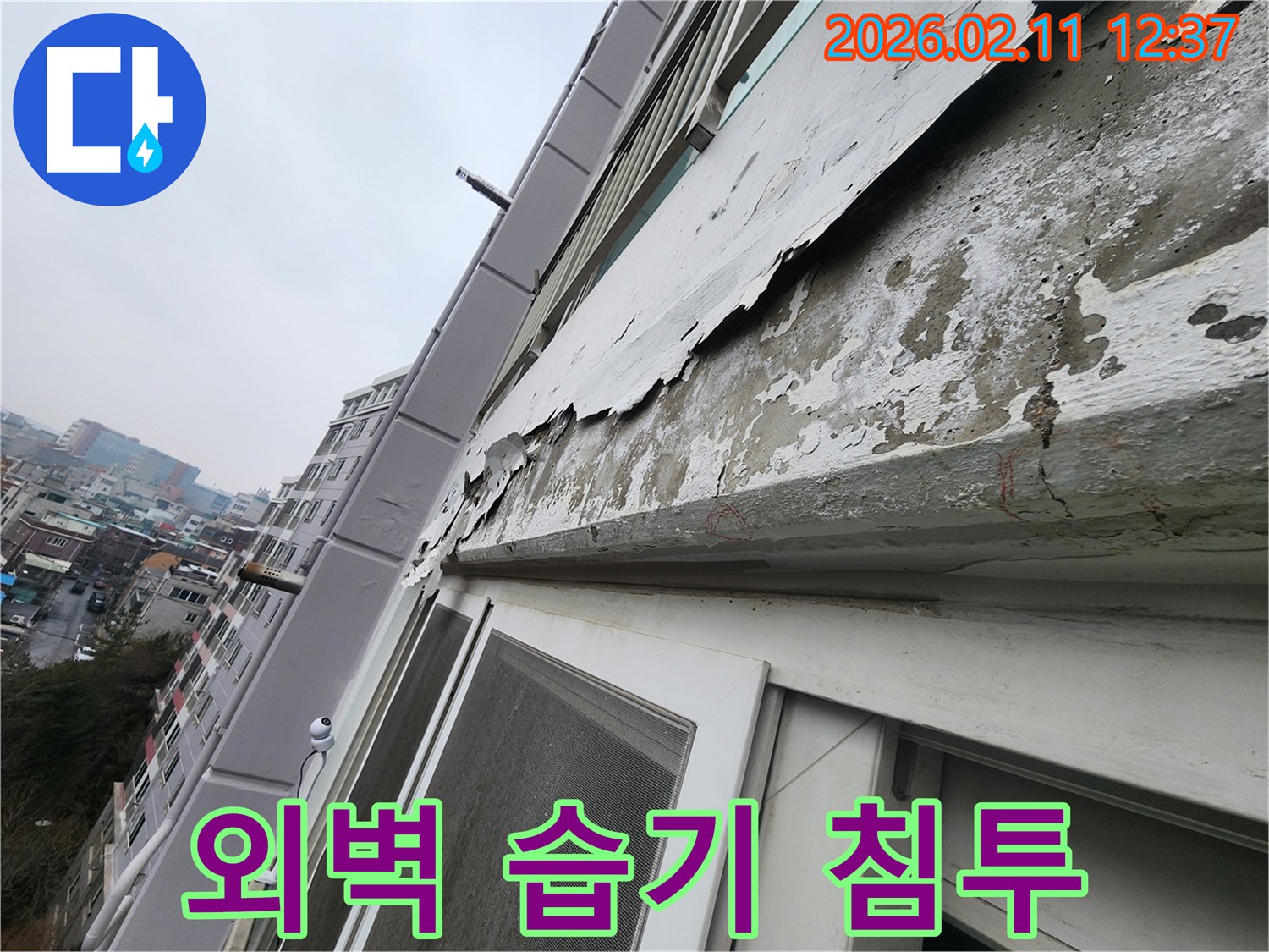 아파트 외벽의 페인트가 벗겨진 틈새로-습기가 침투하여-누수가 발생할 수 있는 상태