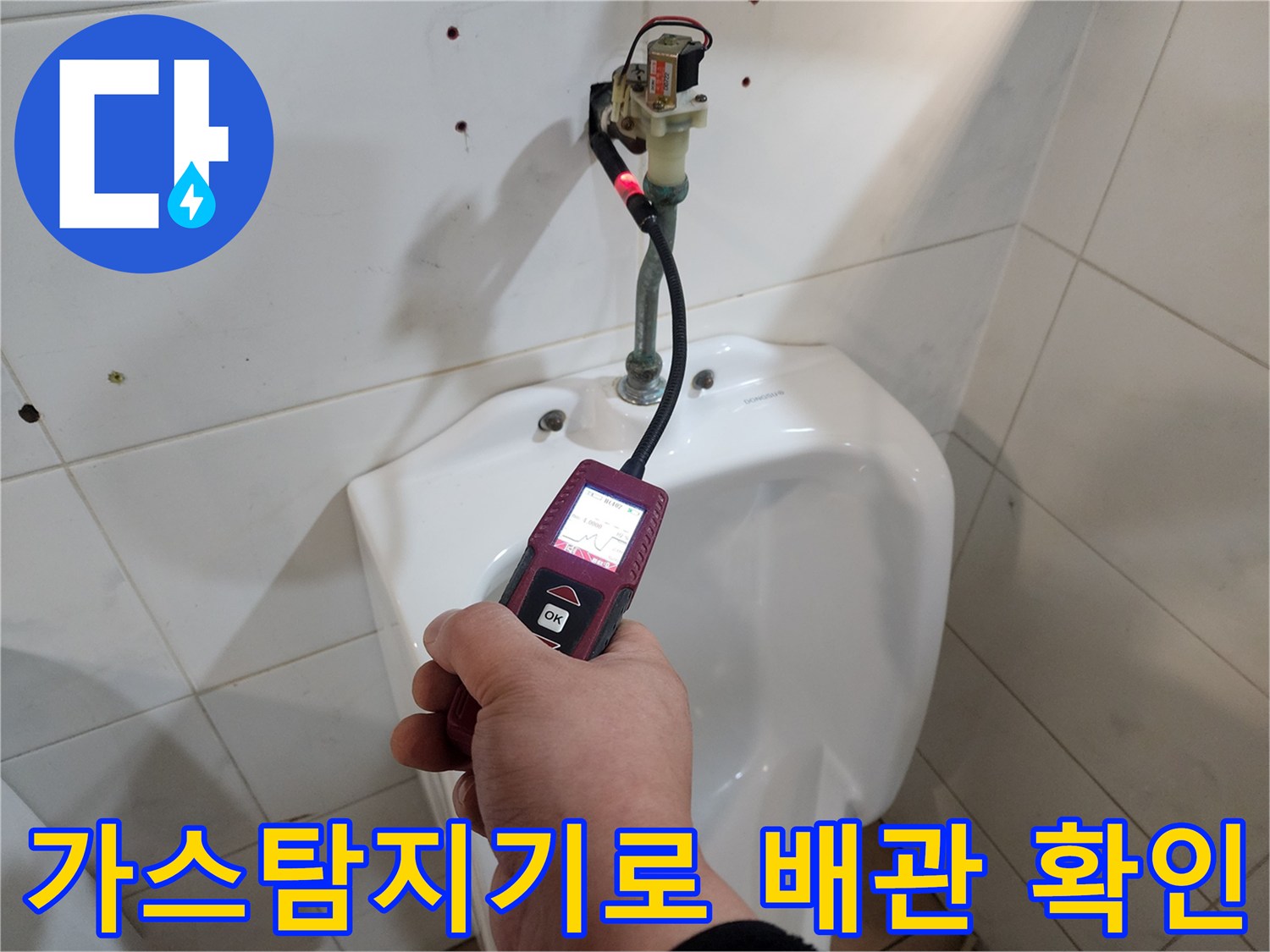 화장실 바닥 부근에서 가스 탐지기를 활용하여 누수 위치를 찾는 모습