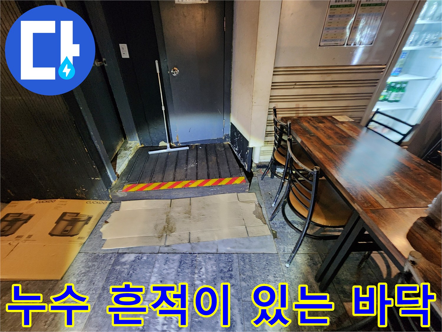 지하 화장실 입구의 젖은 바닥과 문 근처 배관 상태