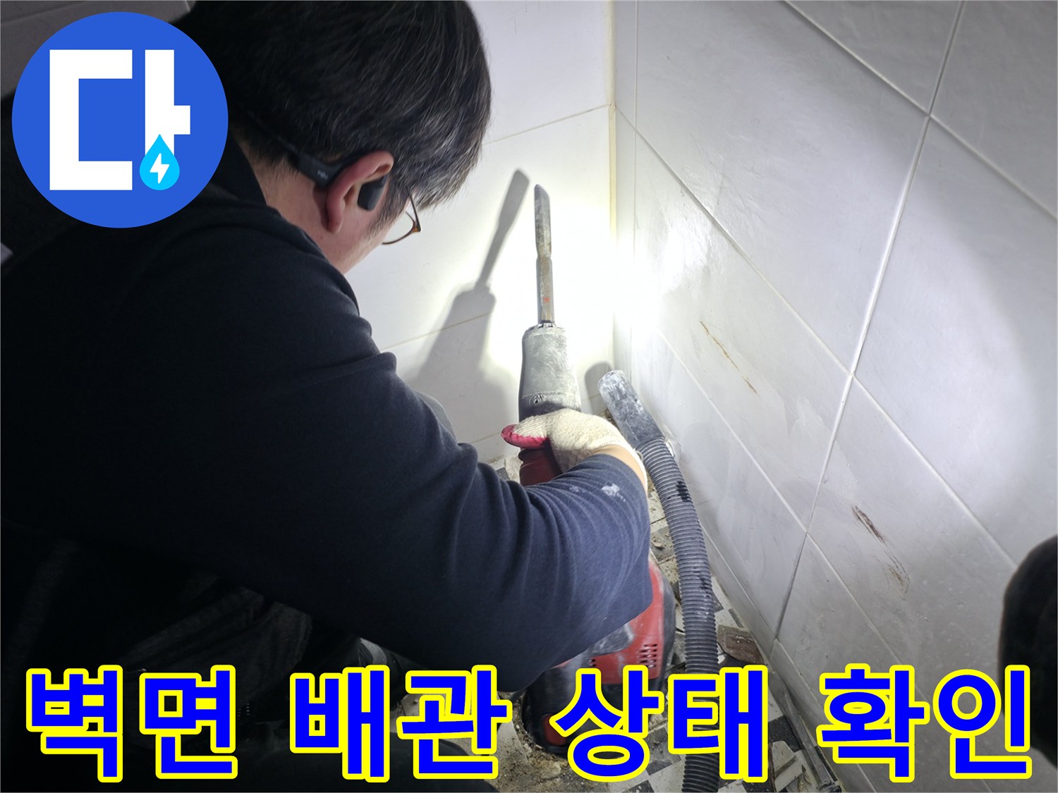 손전등으로 타일 틈새를 비추며 누수 지점을 찾는 탐지 작업
