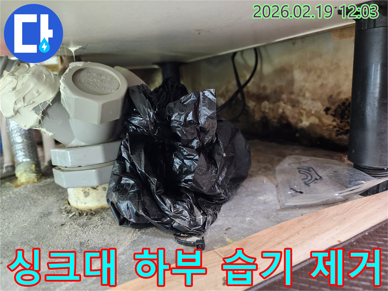 이 이미지는 싱크대 하부의 배관 주변에서 발생한 습기와-곰팡이-그리고 낡은 배관 부속들을 보여줍니다.