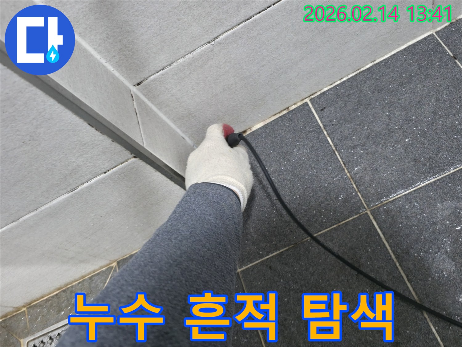 누수 엔지니어가-장갑을 끼고-누수 탐지 장비를 활용하여-타일 틈새에 숨겨진-누수 흔적을 찾아내는 모습입니다.