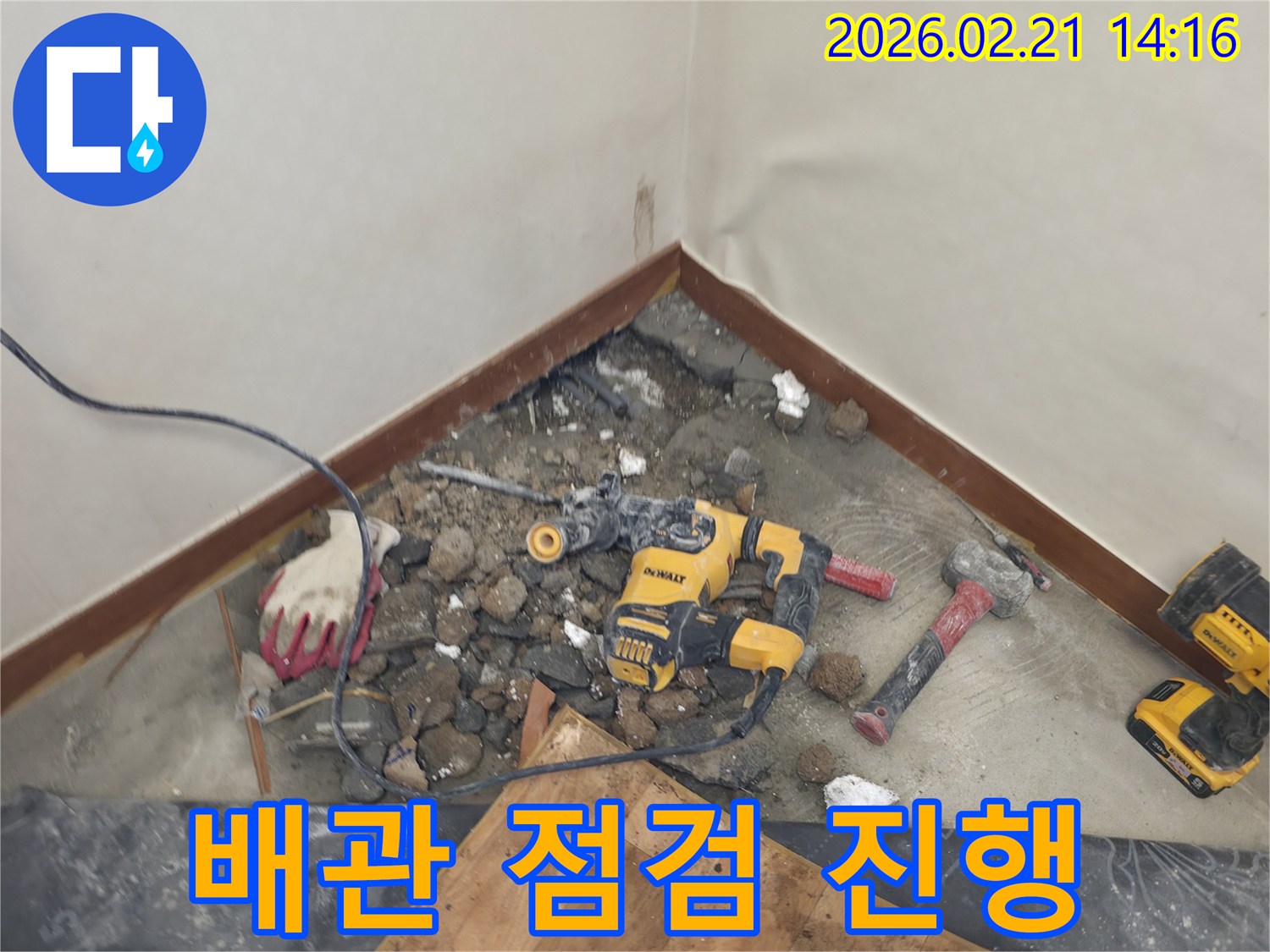 누수 해결을 위해 바닥을 파쇄하고 배관을 점검하는 현장-안전 장비와 함께