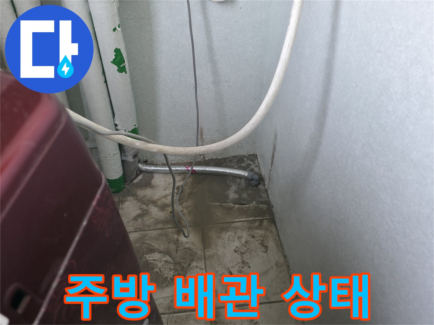 싱크대 아래쪽의 흰색 배관과 은색 금속 관이 연결된 모습입니다.