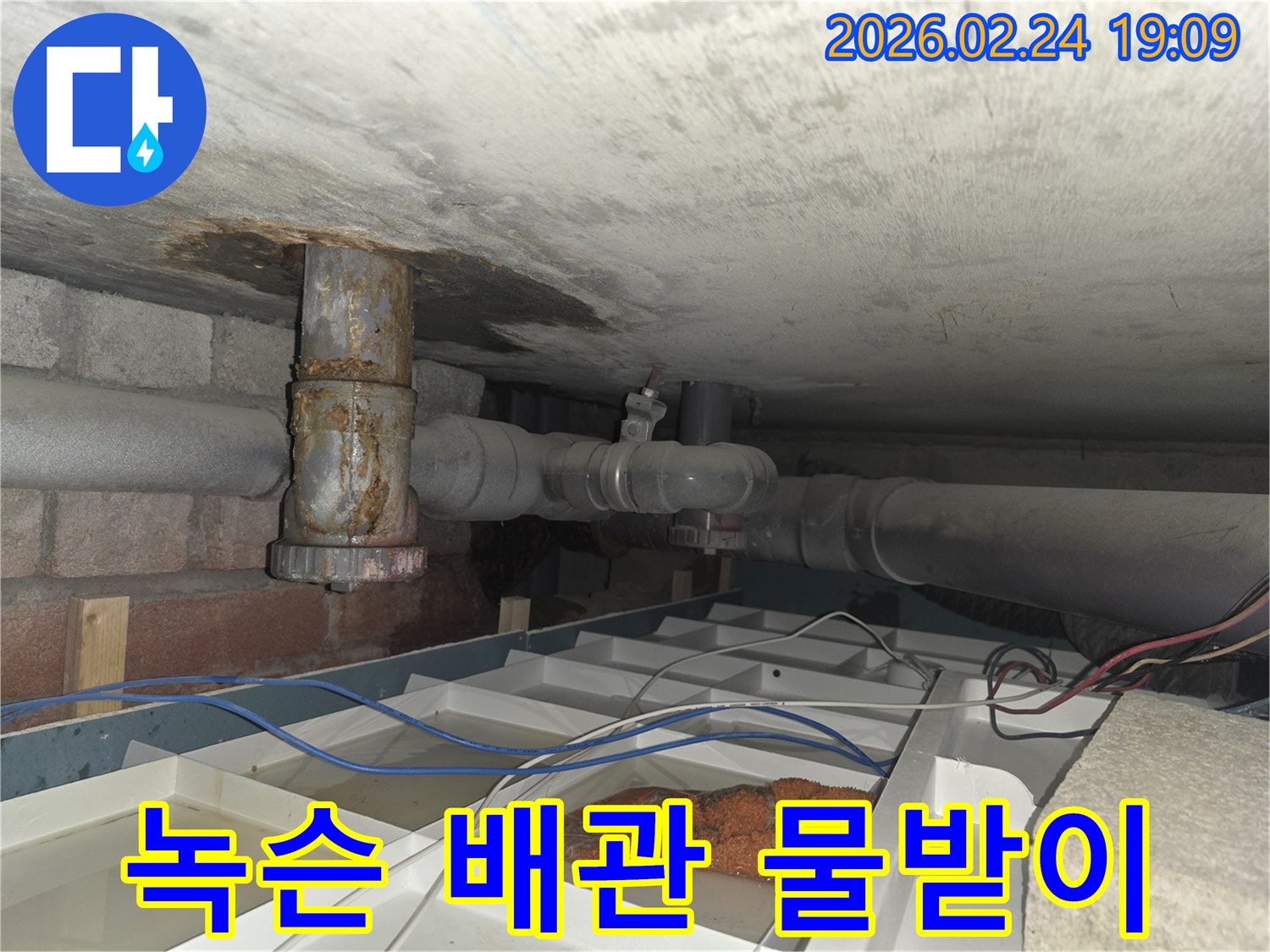 부식된 배관에서-물이 새어 나와-임시 물받이에-고인 물을-보여주는 누수 현장