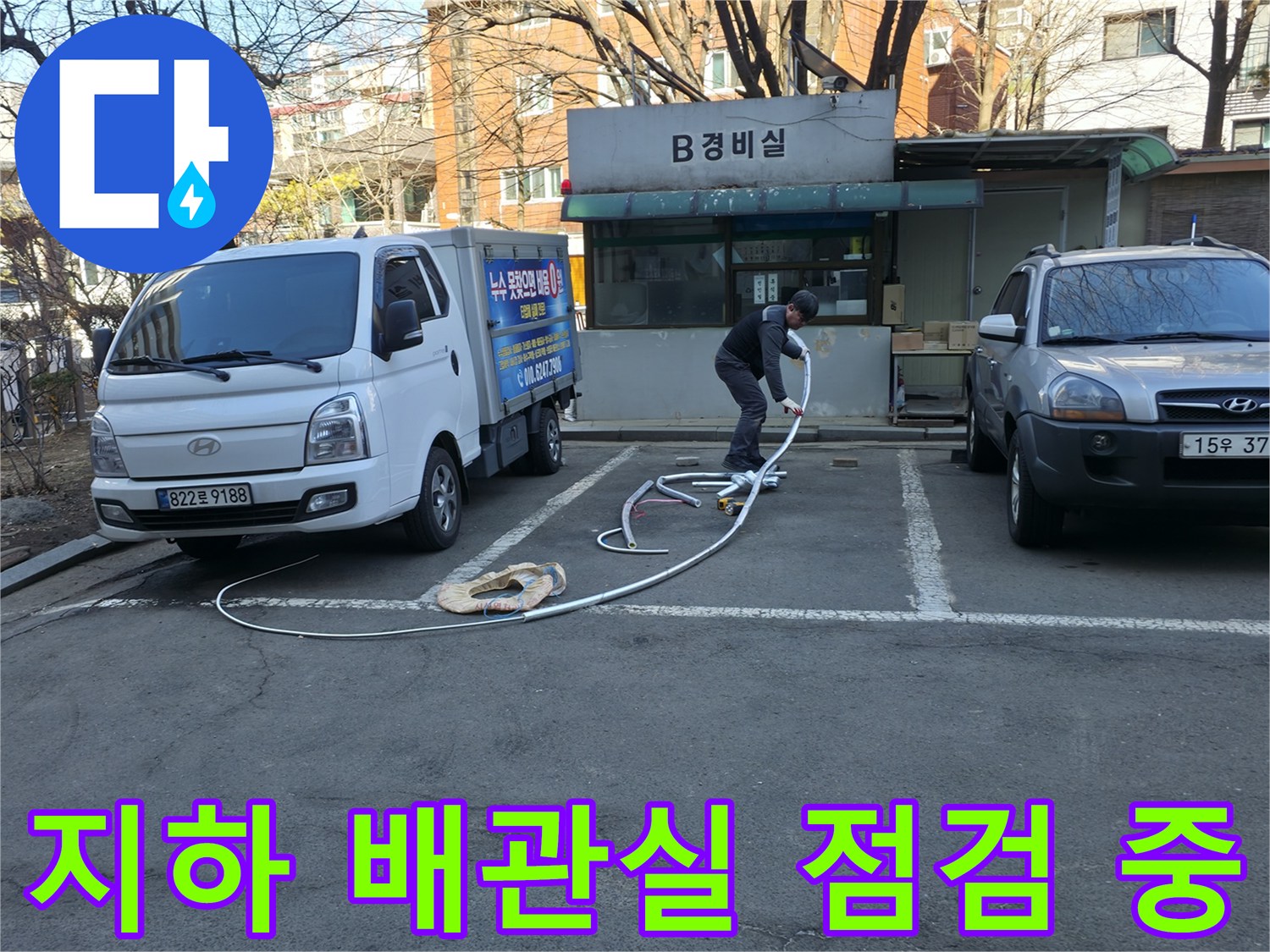 경비실 앞 주차된 차량과 배관 검사를 위해 호스를 전개하는 모습