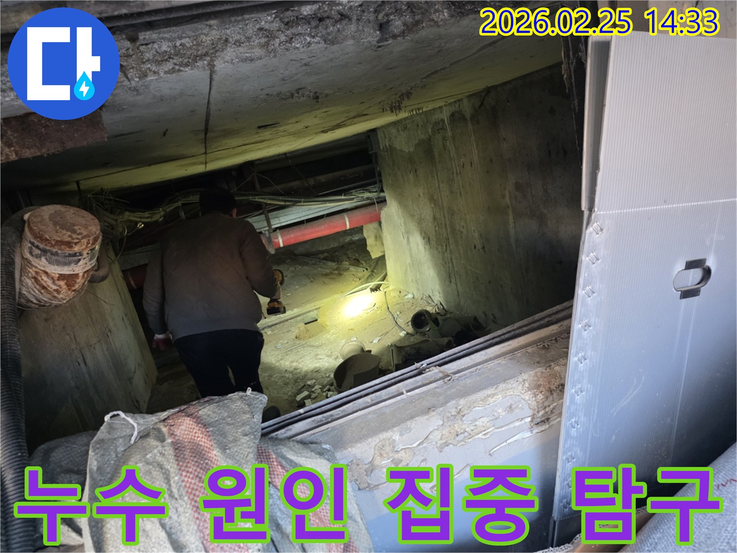 누수 전문 엔지니어가-어둡고 좁은 공간에서-손전등을 비춰가며-배관의 누수 원인을-집중적으로 탐구하여-완벽하게 파악하는 모습입니다.