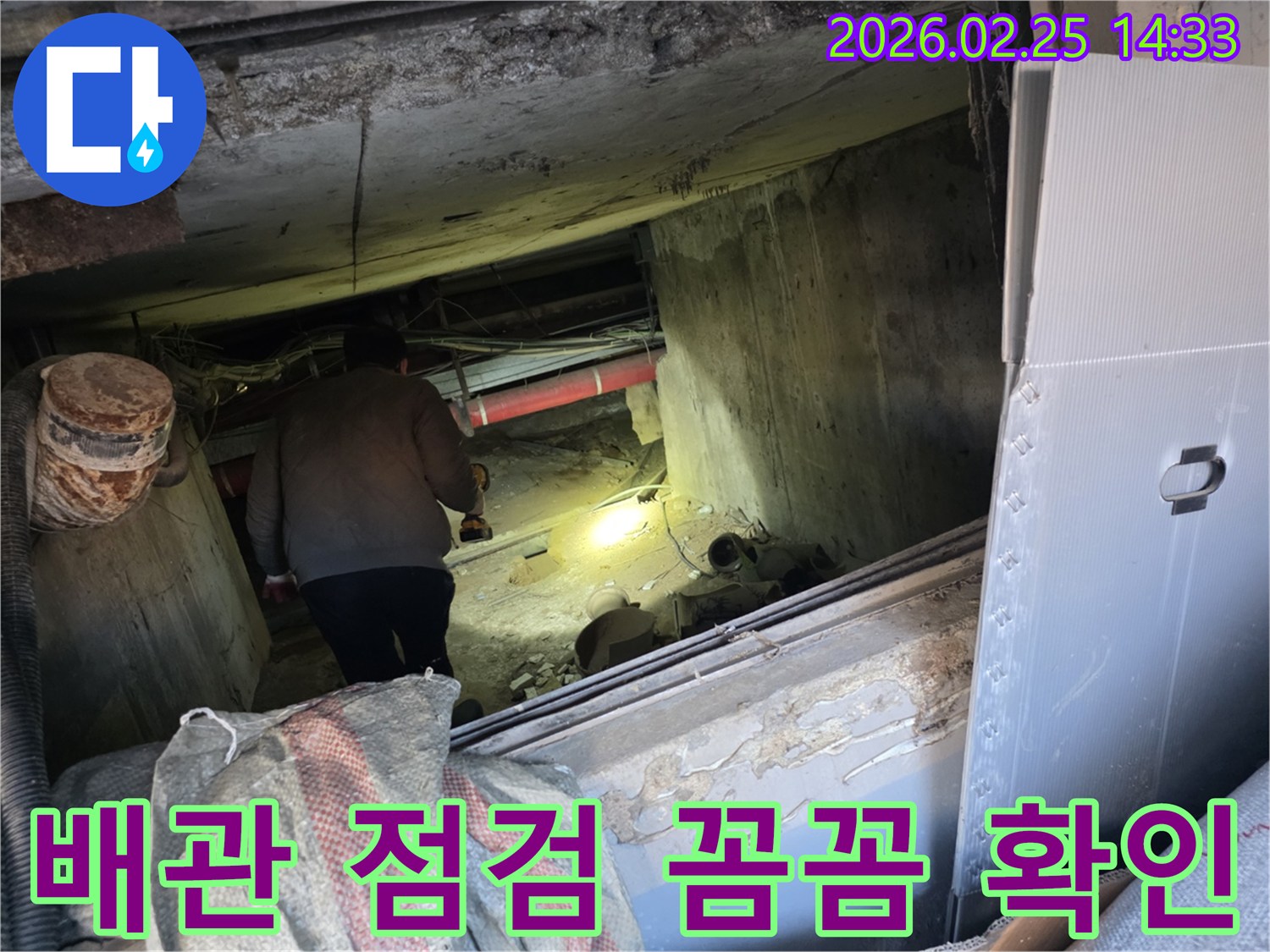 누수 전문 엔지니어가-어둡고 좁은 공간에서-손전등을 비춰가며-배관의 모든 부분을-꼼꼼하게 확인하는 모습입니다.