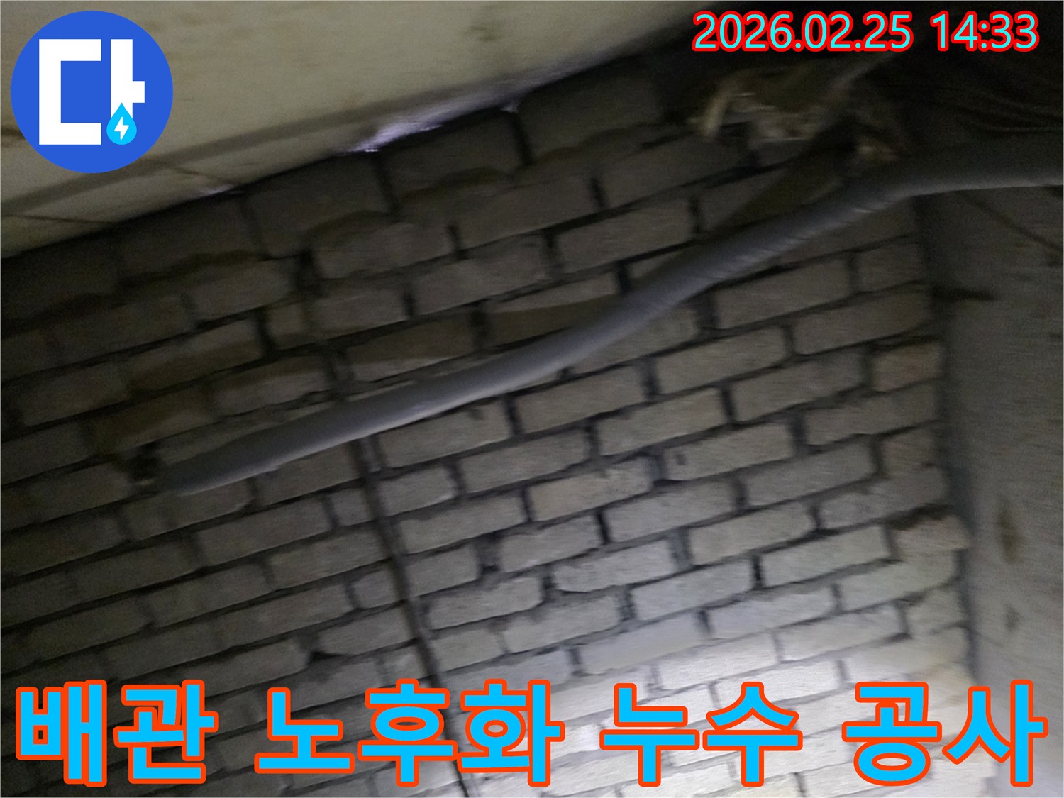 어두운 벽돌 벽면을 배경으로-노후된 배관에서 발생한-누수 공사를 위해-정밀하게 검사되는 현장 이미지입니다.