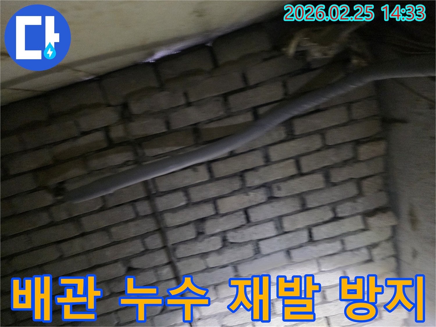 어두운 벽돌 벽면을 배경으로-단열된 배관과 함께-누수 재발 방지를 위해-정밀하게 검사되는 현장 모습입니다.