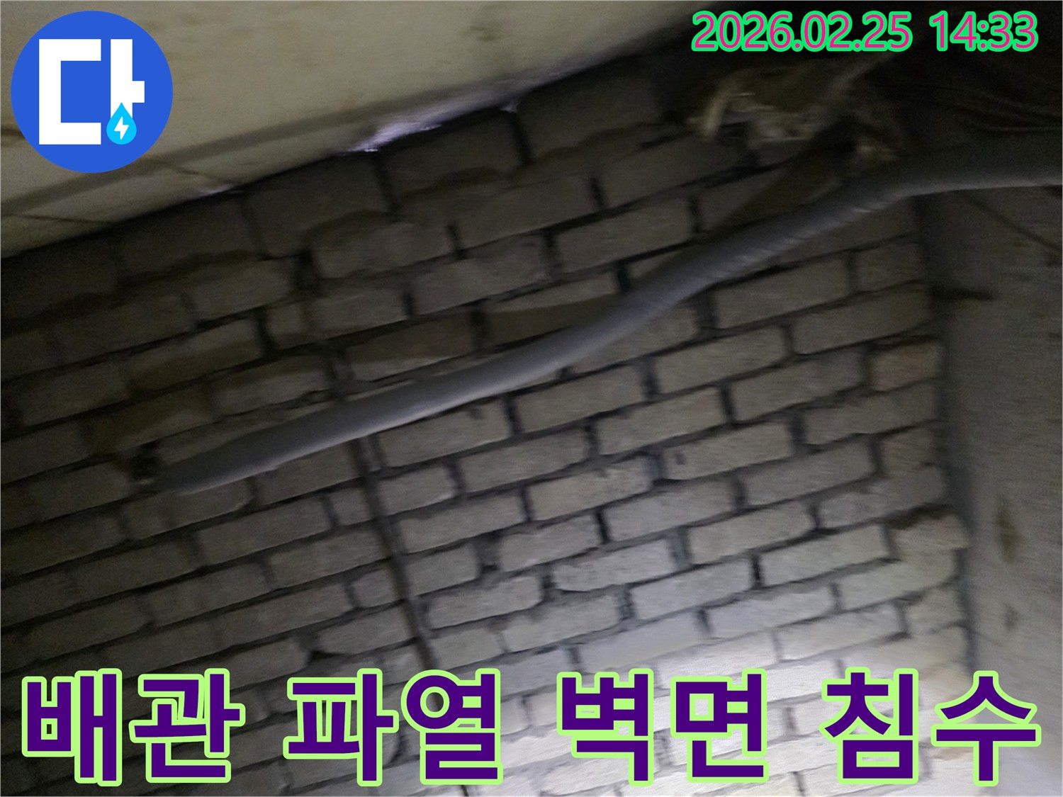 어두운 벽돌 벽면을 배경으로-파열된 배관과 함께-침수 피해를 확인하기 위해-정밀하게 검사되는 현장 모습입니다.