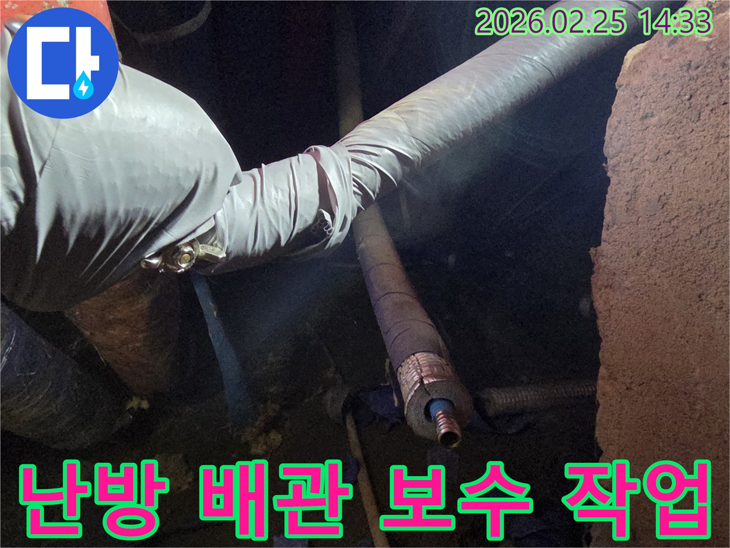 어두운 작업 공간에서-장갑을 낀 손이-손상된 난방 배관의-연결 부위를-꼼꼼하게 보수하는-모습을 담고 있습니다