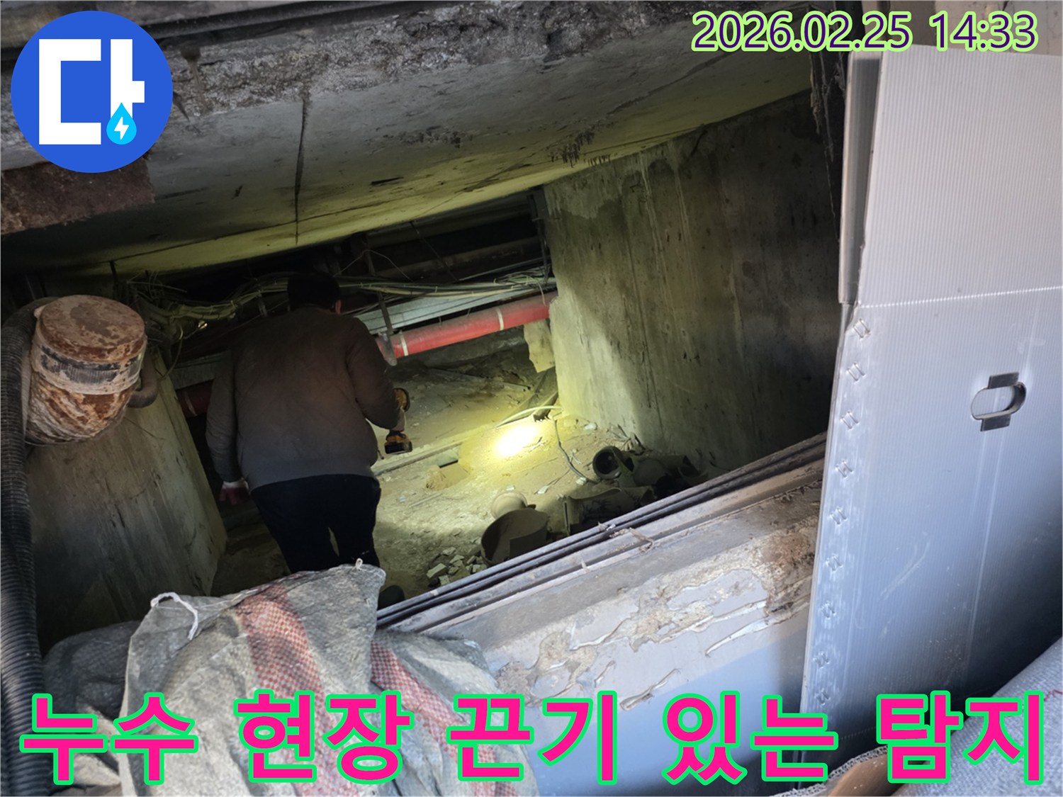 어둡고 좁은 공간에서-누수 전문 엔지니어가-손전등으로 배관을 비추며-끈기 있게 누수 지점을-탐지하는 전문적인 모습입니다.