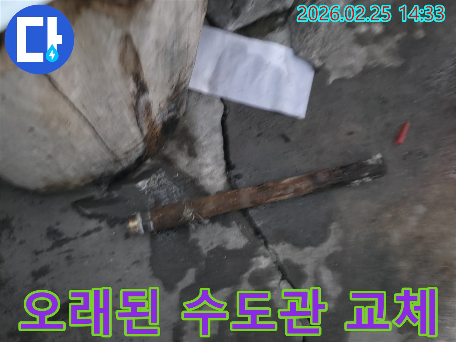 오래되어 녹슬고-파열된 수도관이-젖은 콘크리트 바닥에 놓여있는-누수 현장 사진입니다.