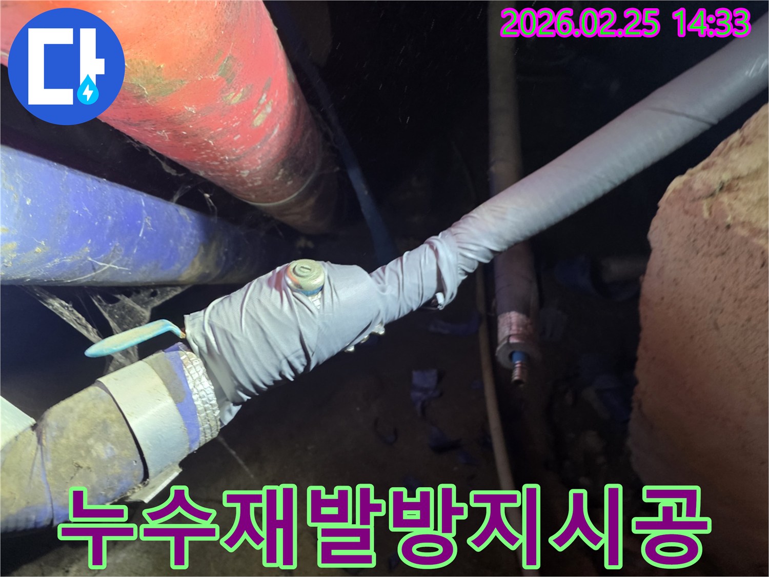 이 이미지는 누수 탐지를 위해 배관에 압력 측정 장비를 연결하는 전문 엔지니어의 모습을 보여줍니다-정확한 누수 지점을 찾기 위한 핵심 과정입니다