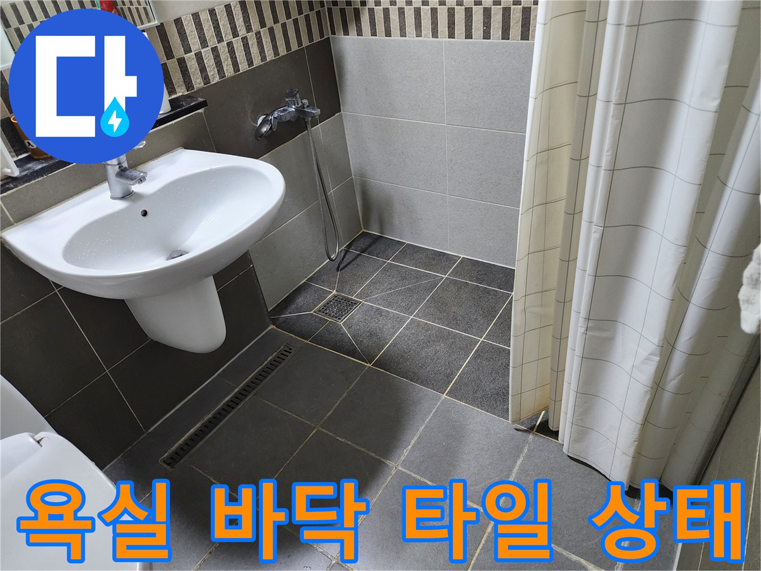 세면대 아래 욕실 바닥 타일과 배수구 주변 모습입니다.