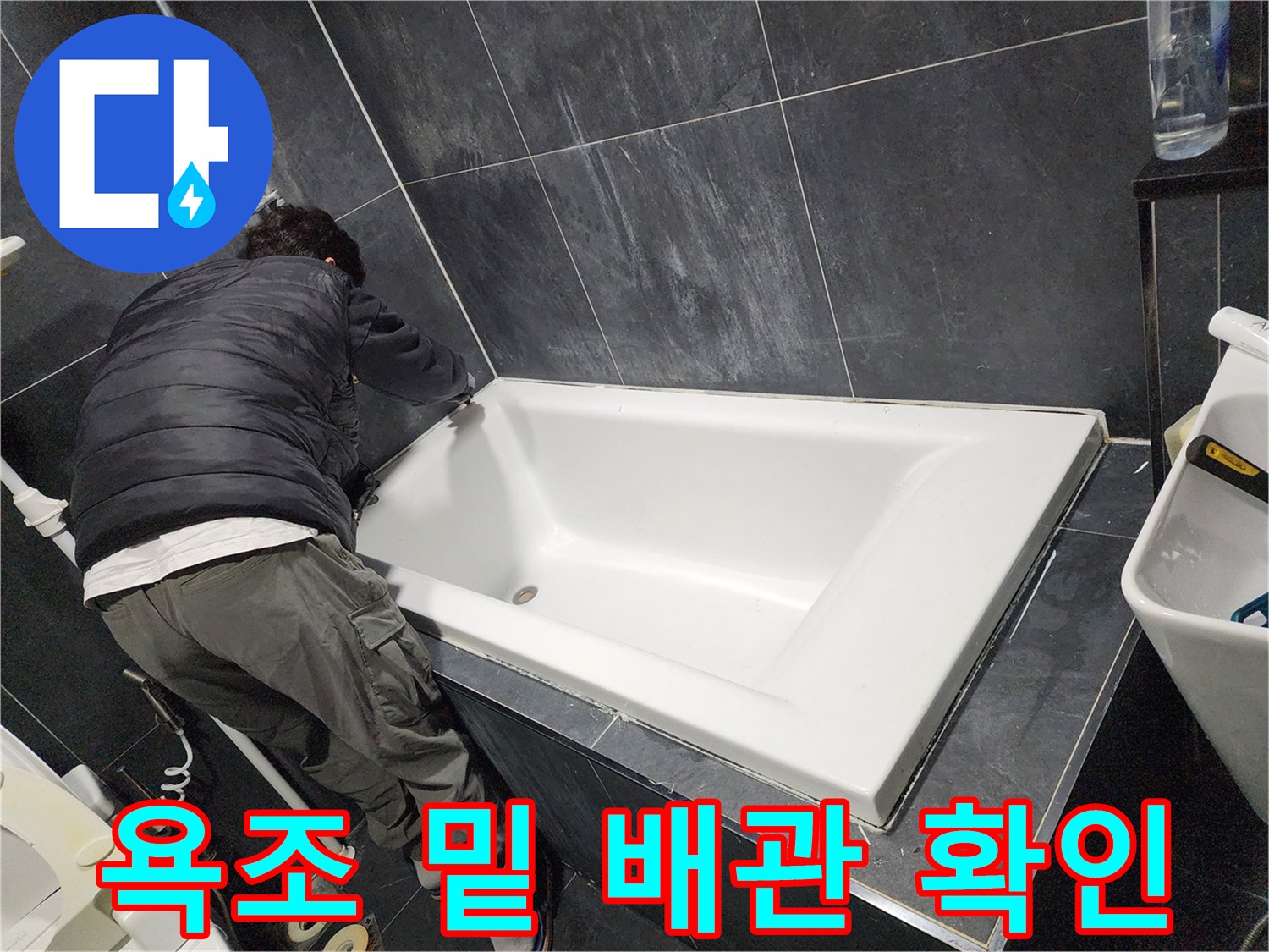 욕조 아래 공간의 배관 상태를 점검하는 모습