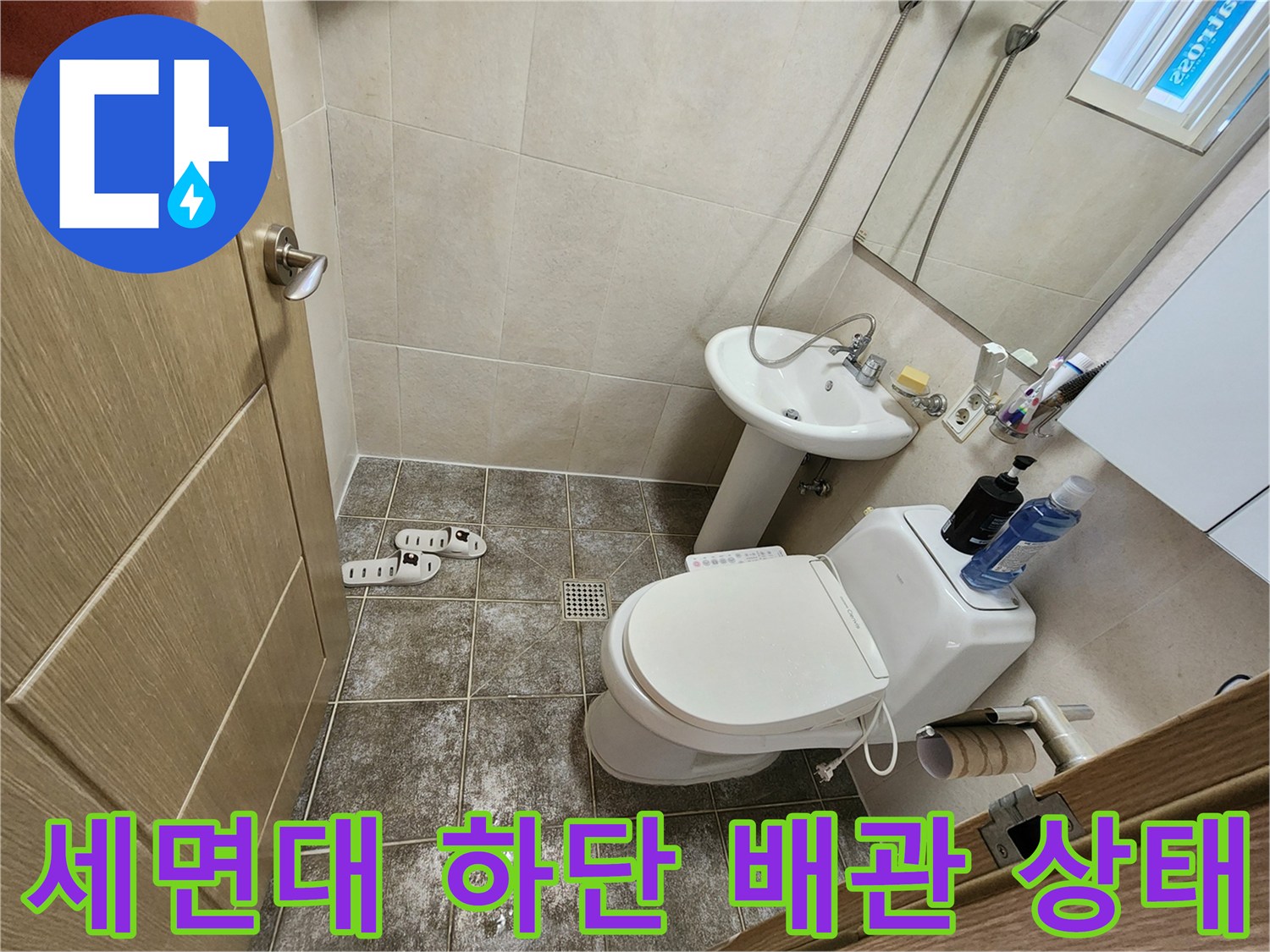 화장실 세면대 아래쪽의 급수 배관과 타일 마감 상태를 보여주는 사진입니다.