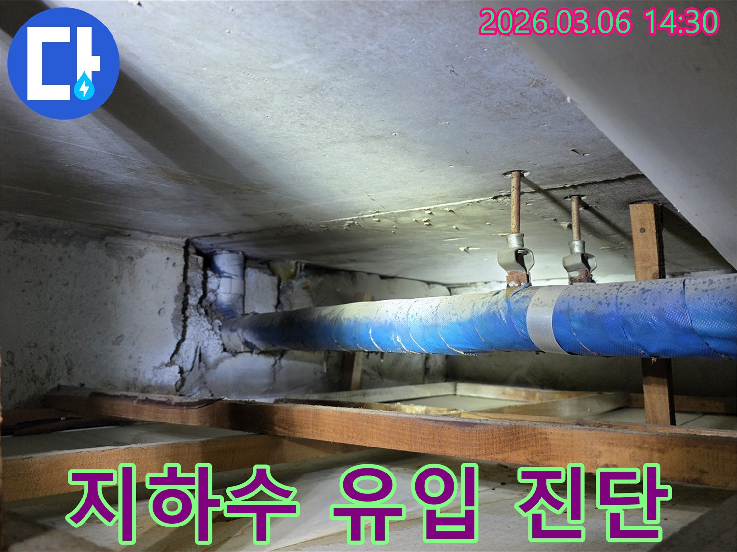 지하 공간의 파란색 배관 주변-누수로 인해 손상된 콘크리트 벽면을-누수 엔지니어가-지하수 유입 여부를-정밀 진단하는 모습