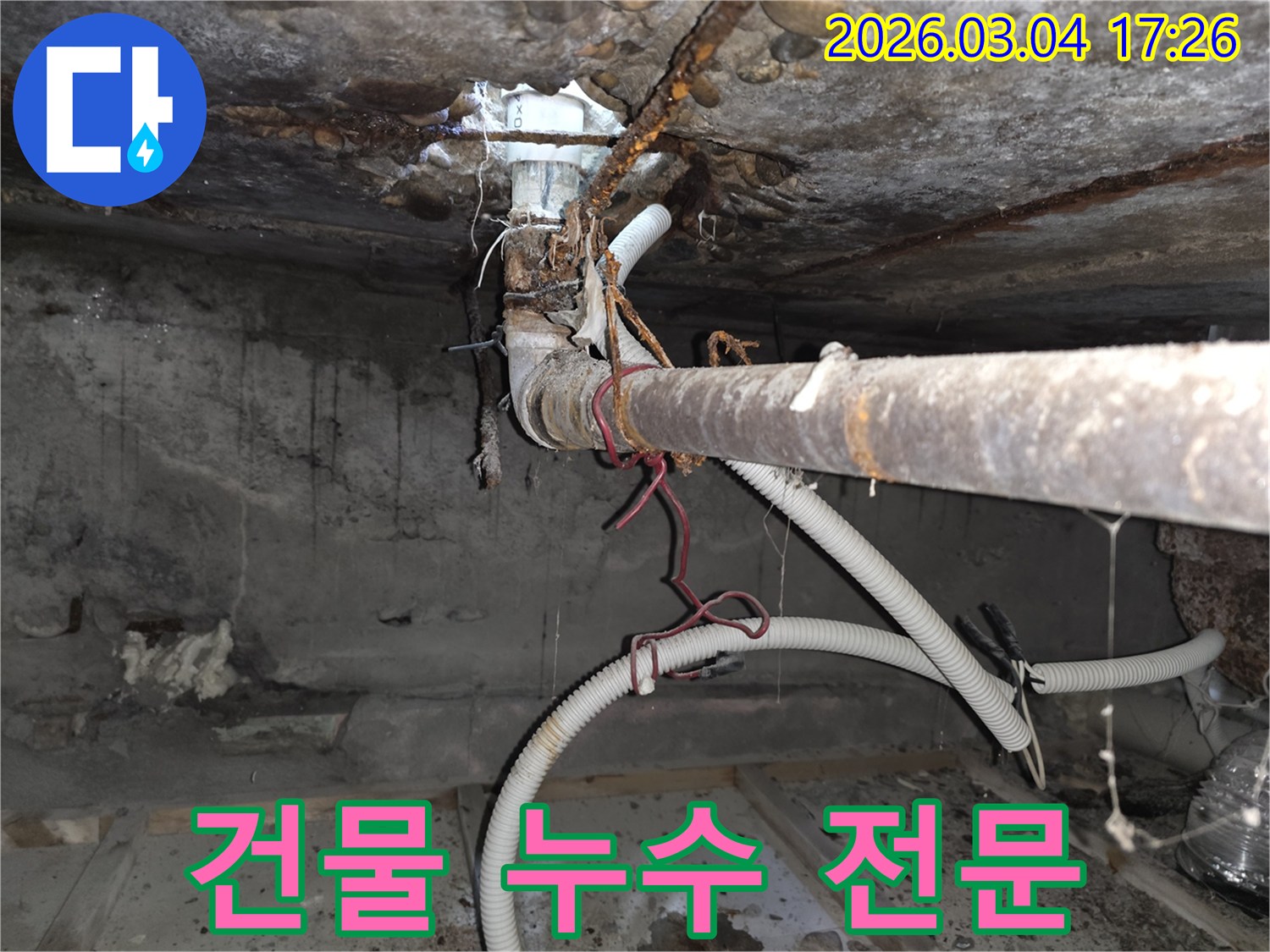 오래된 건물-지하 배관의-심각한 부식으로-인한 누수 현장을-전문가가-점검하고-해결하는-모습을-담은 사진입니다