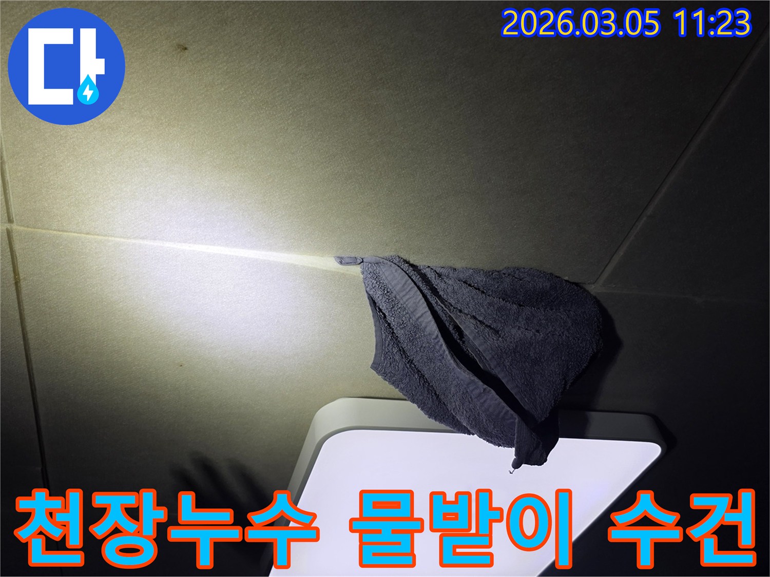 누수로-인해-천장-등기구-주변에-물이-떨어져-수건으로-임시-조치한-모습을-담은-사진
