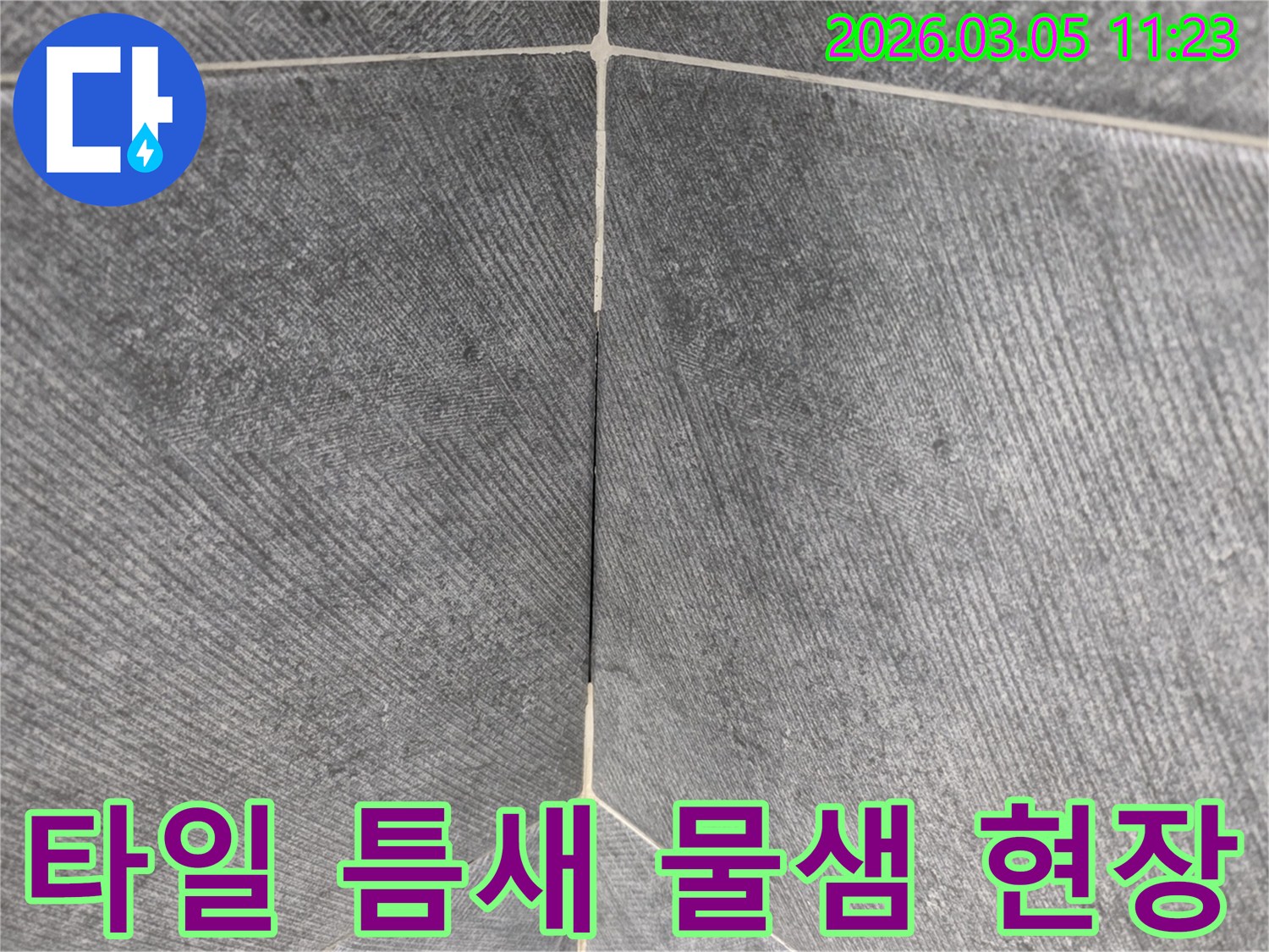 타일 사이의-미세한 틈새를 통해-물이 새어 나오는-현장을 포착한-클로즈업 이미지입니다.