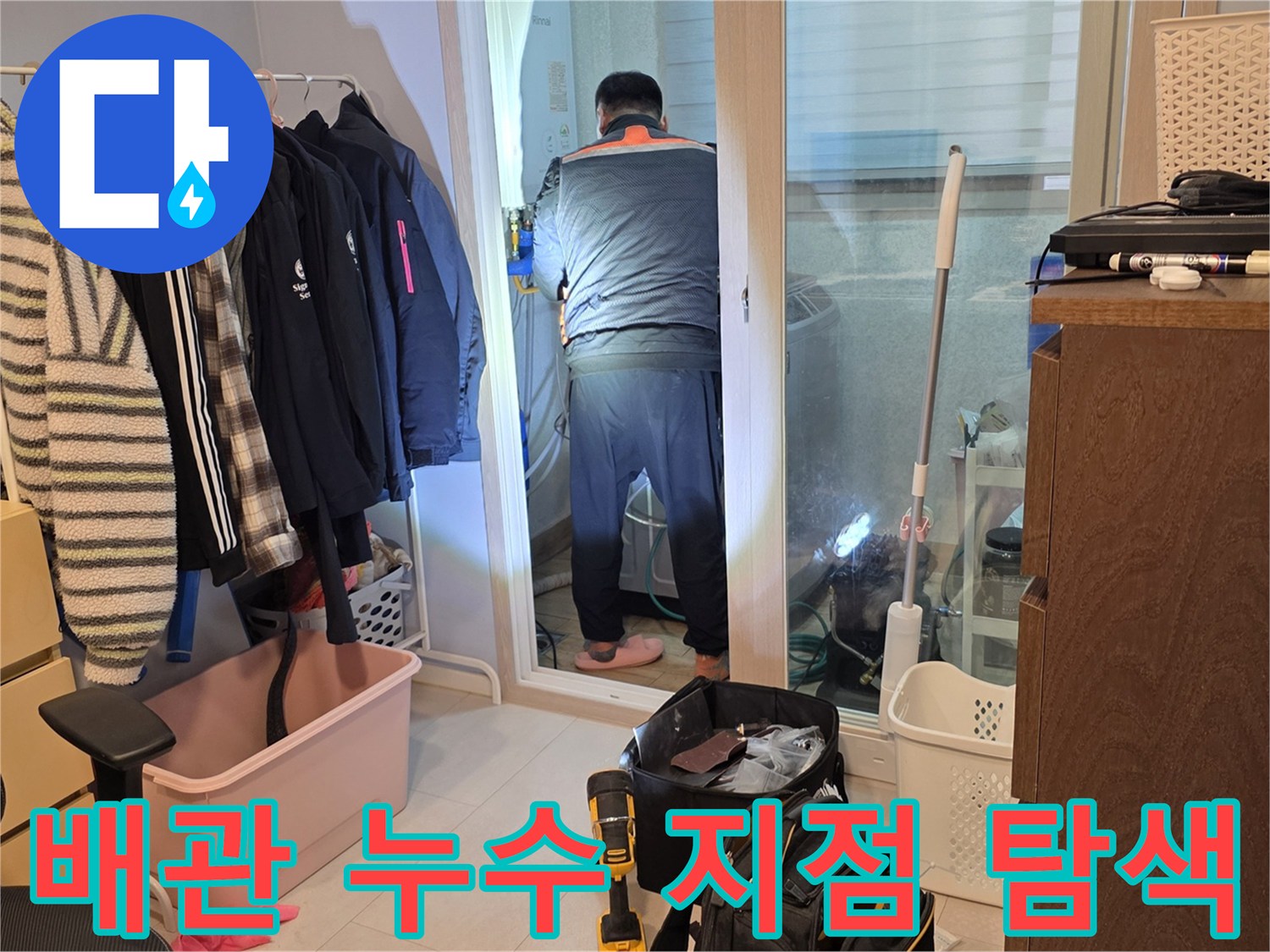 세탁실 내부 공간에서 수도 배관의 이상 유무를 확인하는 작업자