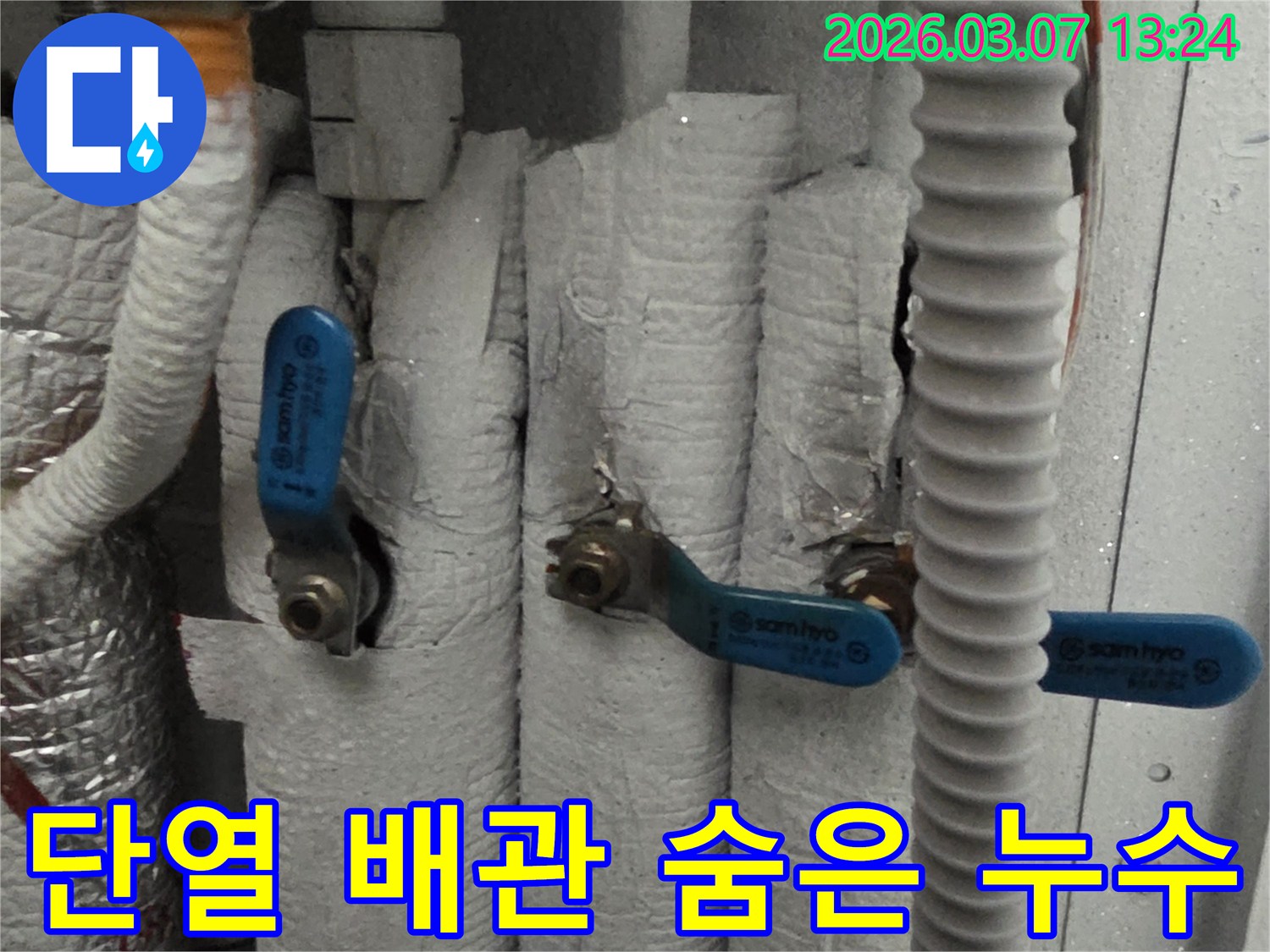 두꺼운 단열재로 감싸진 배관 아래 숨겨진 누수 지점을 찾아내기 위해 정밀 탐지 장비를 활용하는 모습입니다.