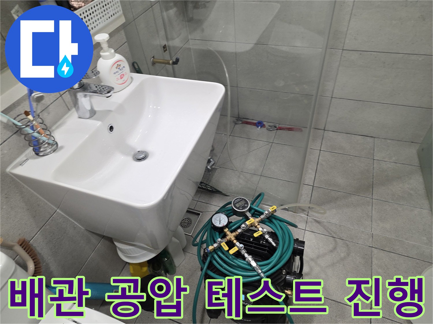 세면대 하단 밸브에 연결된 압력 게이지와 호스 장비