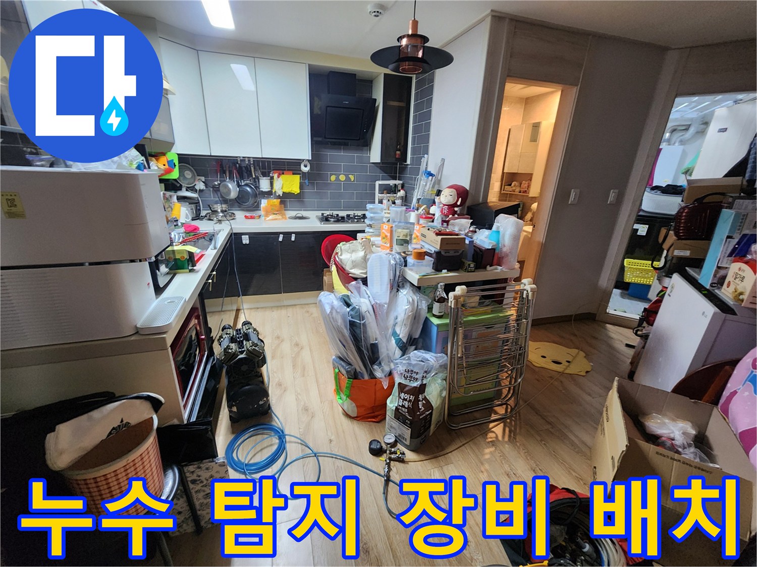 주방 바닥에 연결된 파란색 호스와 압력 테스트를 위한 계측기 모습입니다.