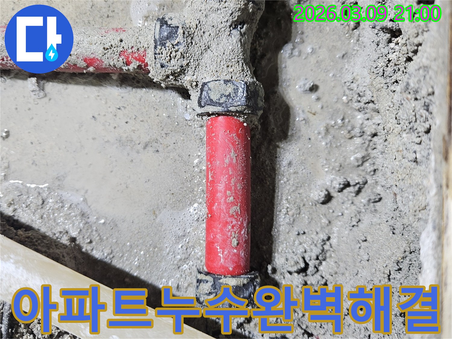 젖은 시멘트 바닥에-매립된 빨간색 배관의-누수 지점을-아파트 환경에 맞춰-정확히 찾아내어-보수한 모습입니다