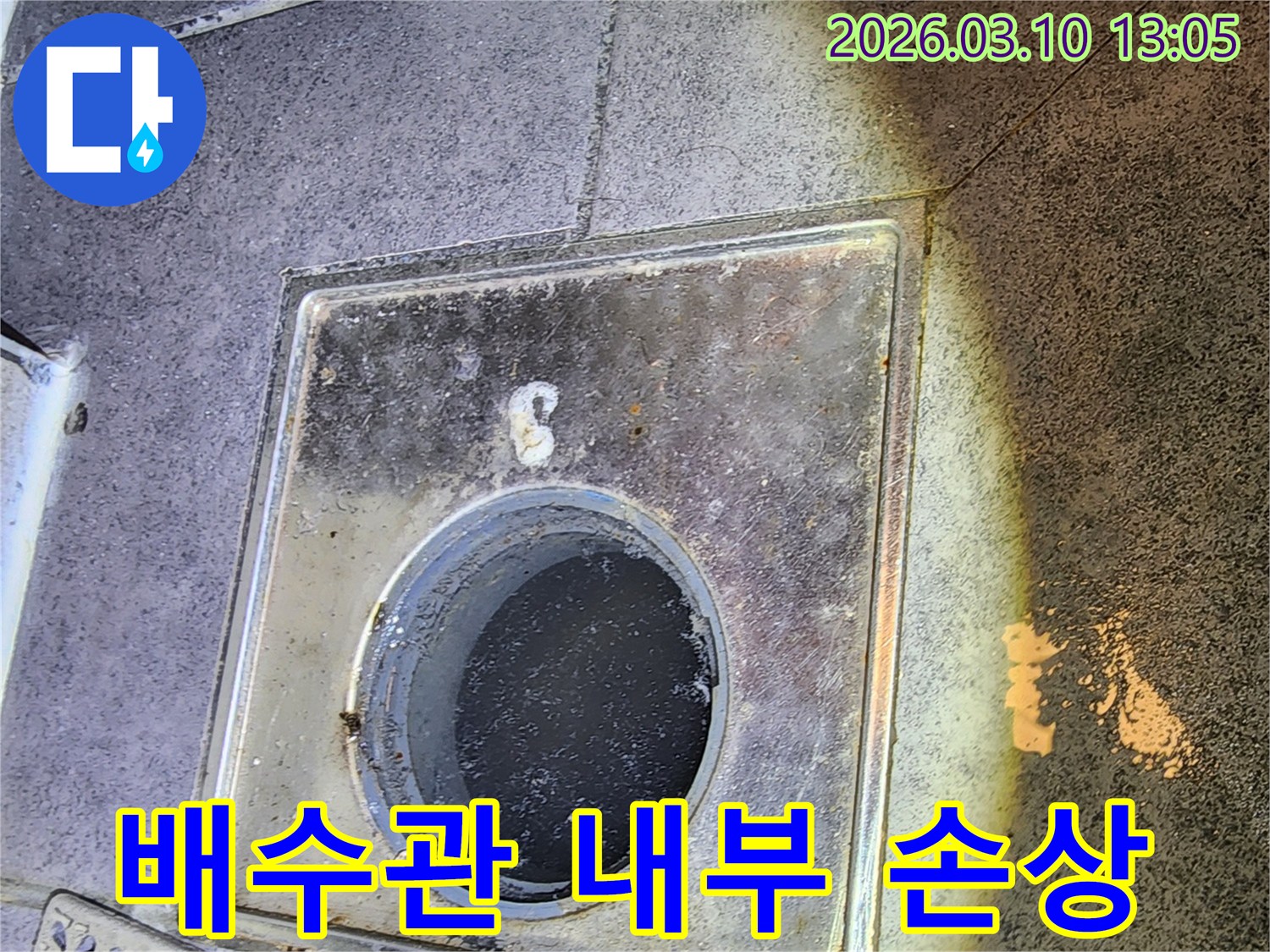 누수 엔지니어가 바닥 배수구 덮개를 열고-배수관 내부의 손상 여부를 육안으로 확인하는 모습입니다