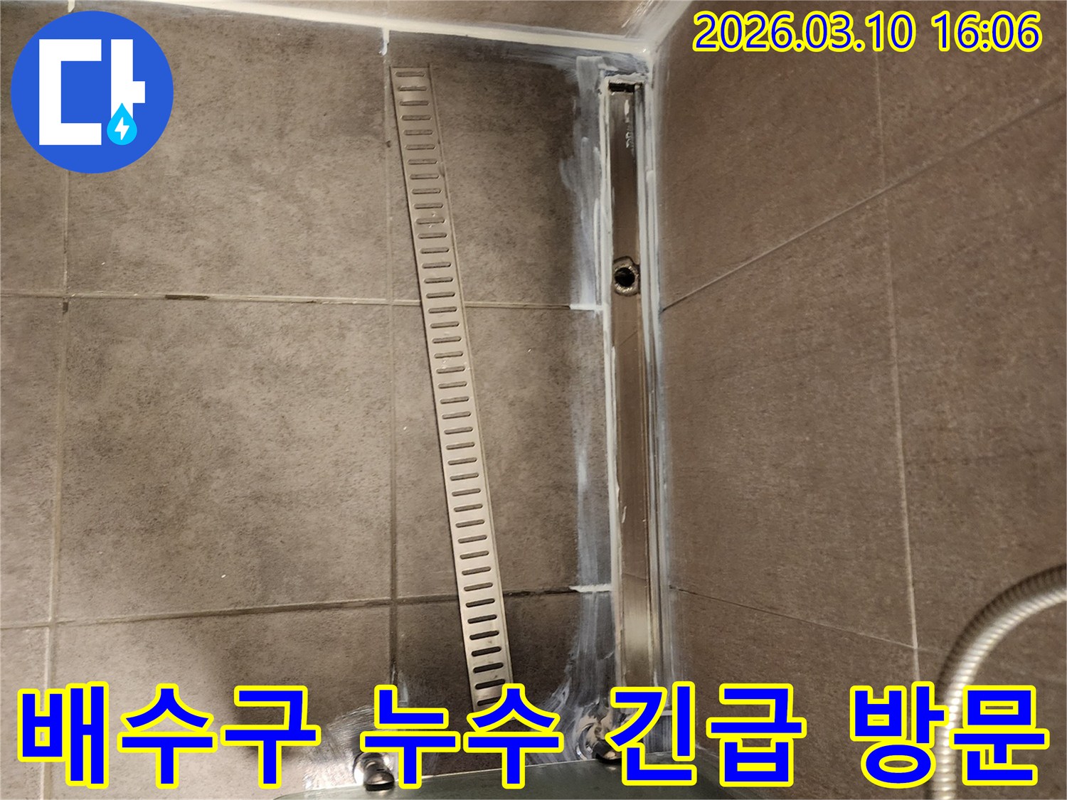 샤워실 바닥의 선형 배수구-주변에서 발생한 누수로 인해-전문 엔지니어가 긴급 방문하여 점검하는 모습입니다