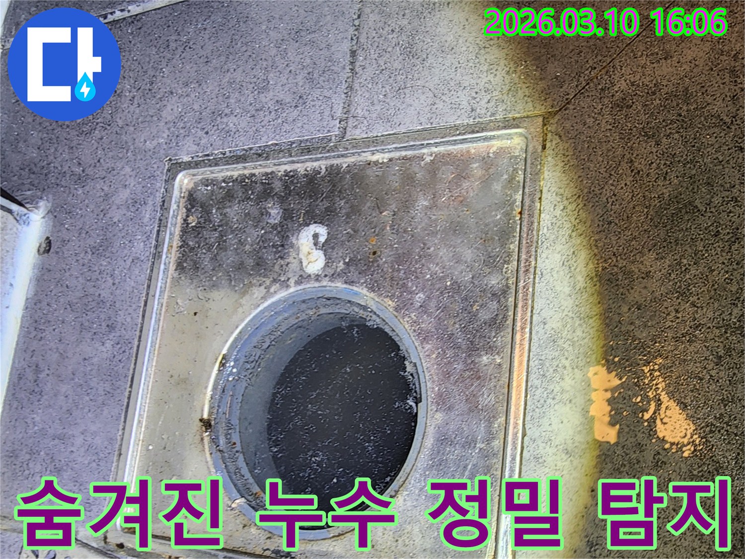 이 이미지는-서울 중구의 한 건물에서-전문 누수 엔지니어가-첨단 장비를 활용하여-육안으로 확인하기 어려운-숨겨진 배수구 누수를-정밀하게 탐지하는-현장을 보여줍니다