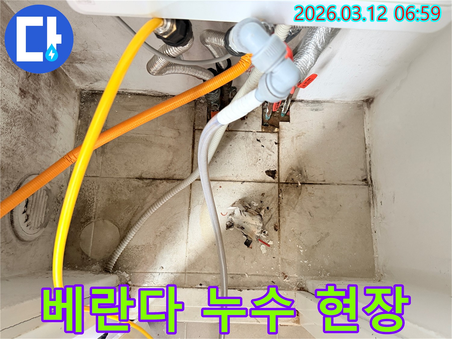 베란다 바닥의-오염된 타일과-벽면의 곰팡이-그리고 복잡한 배관들이-누수 문제를 시사하는-현장 사진입니다.