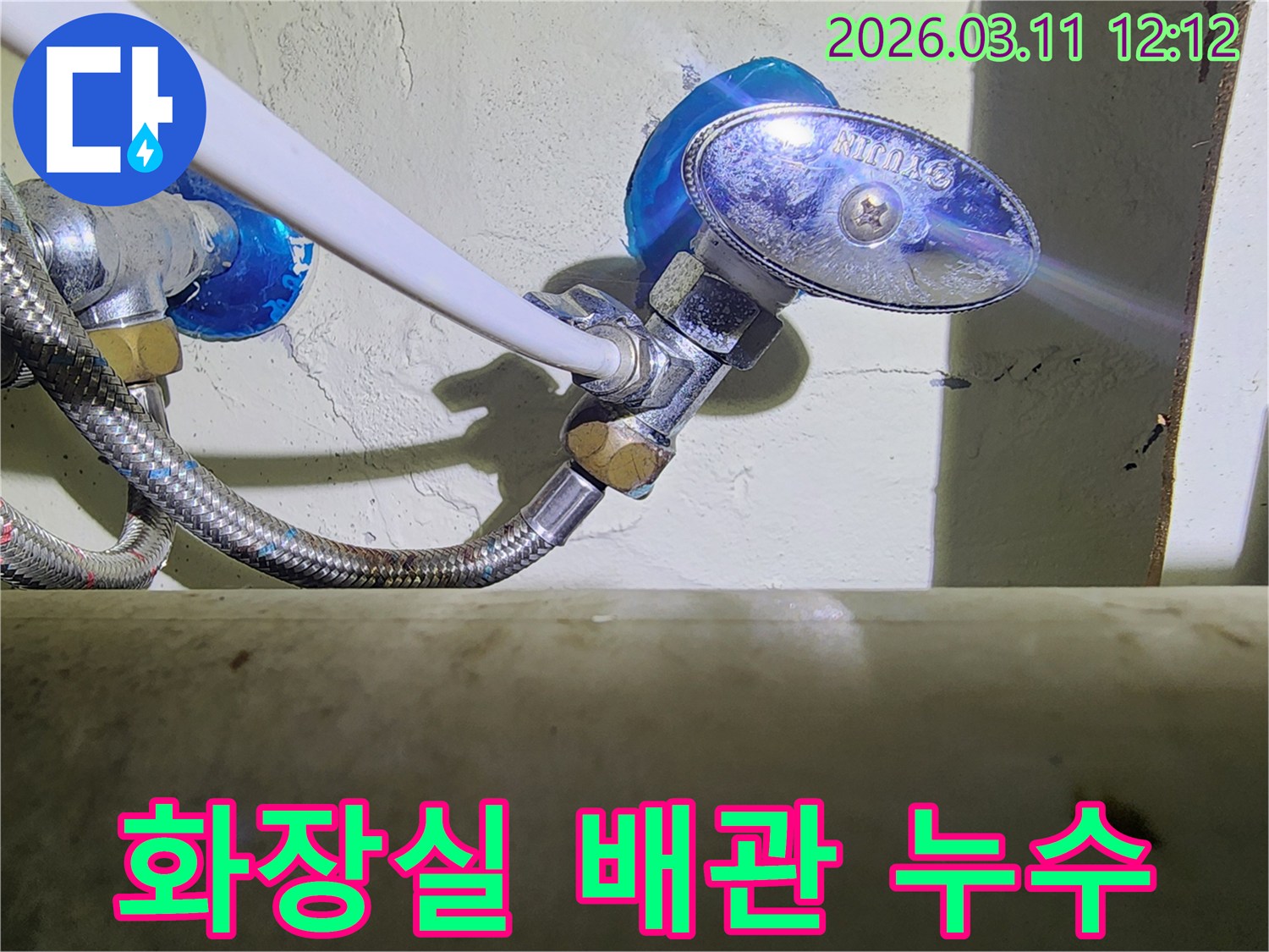 화장실-벽면에-설치된-수도-배관의-앵글밸브와-고압호스-연결부에서-발생한-누수-현장을-보여주는-사진입니다.