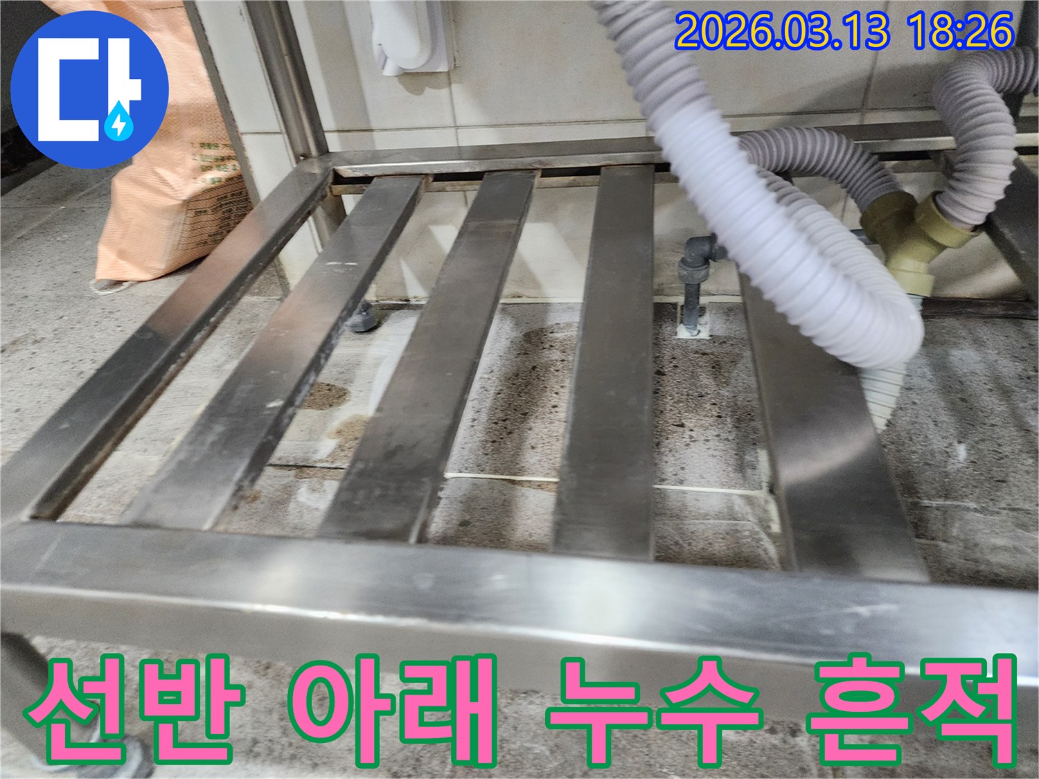 누수-현장에서-스테인리스 선반 아래-물기와 오염으로-변색된 바닥을-정밀하게 점검하는 모습
