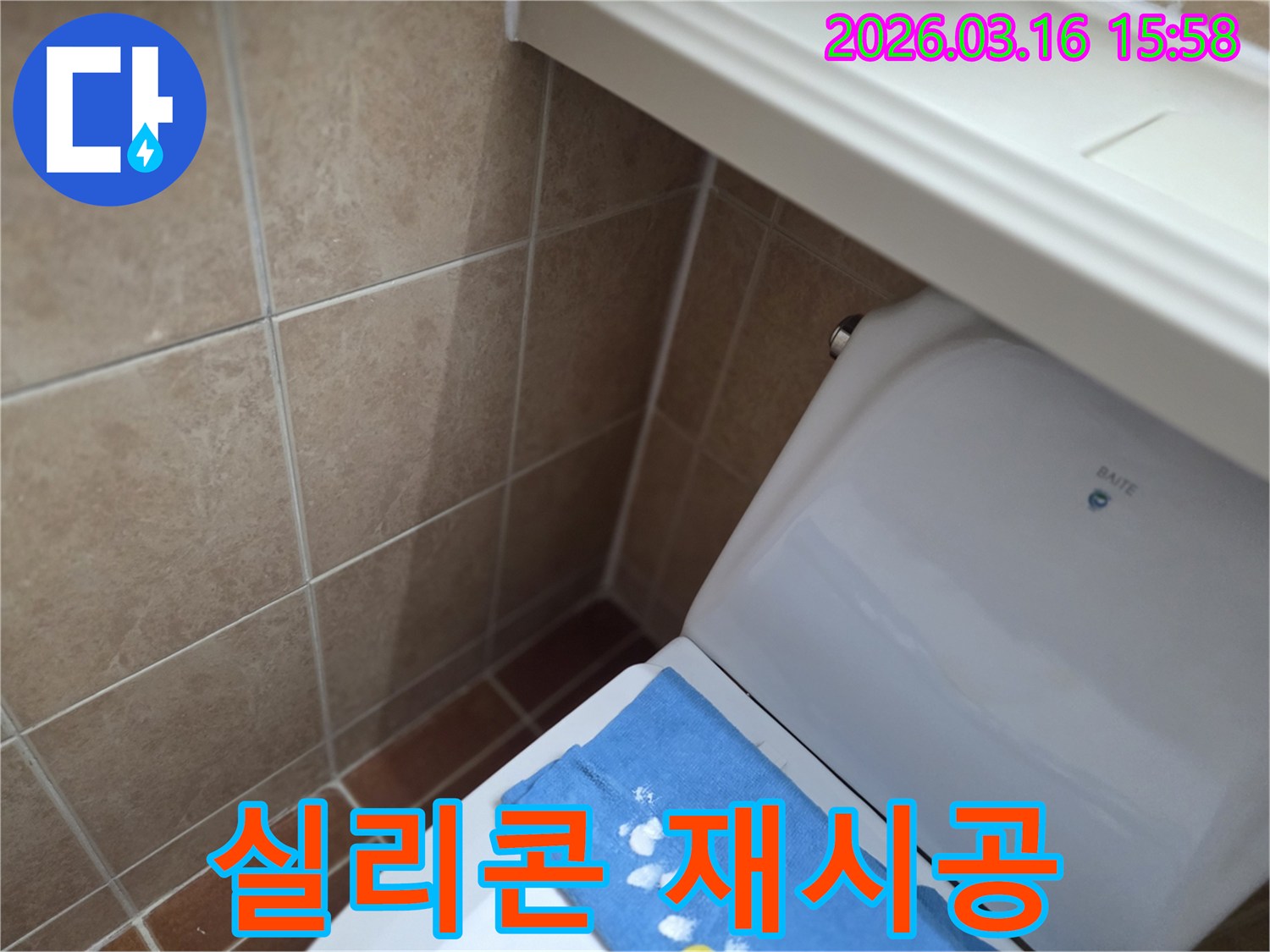 오산시 운암동의-한 욕실에서-변기 뒤편-벽면 타일의 젖음으로-누수 수리 완료 후-변기 주변에-실리콘을 재시공하는-현장을 보여주는-사진입니다.