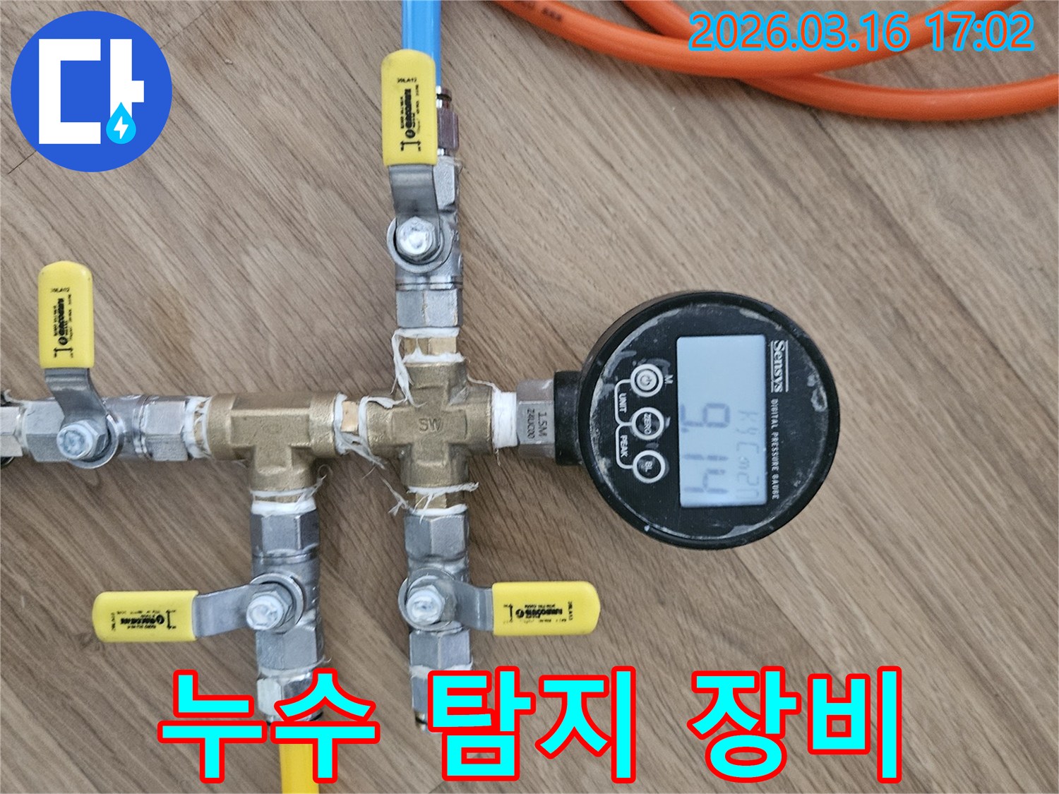 누수 탐지 전문가가-배관의 건전성을 확인하고자-압력 테스트 장치를 설치하고-압력계의 수치를-주의 깊게 관찰하는-장면입니다.