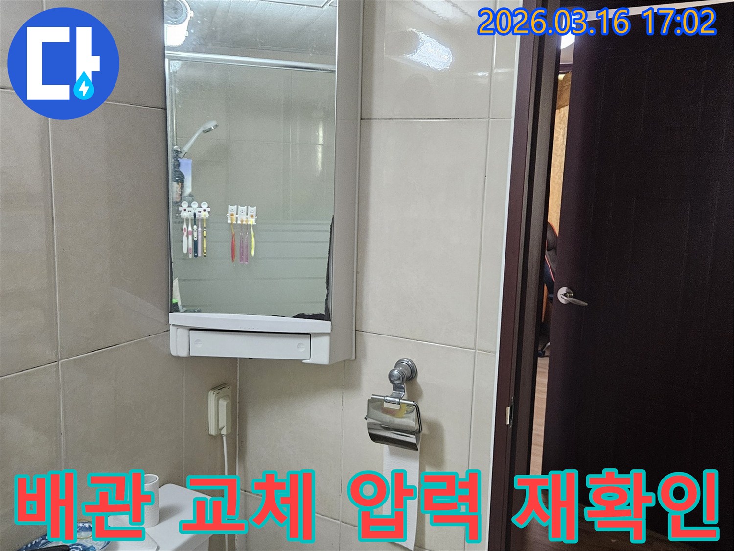 빌라 화장실의-타일 벽면-거울 수납장-변기-창문이 보이는-배관 교체 후 압력 재확인 현장입니다