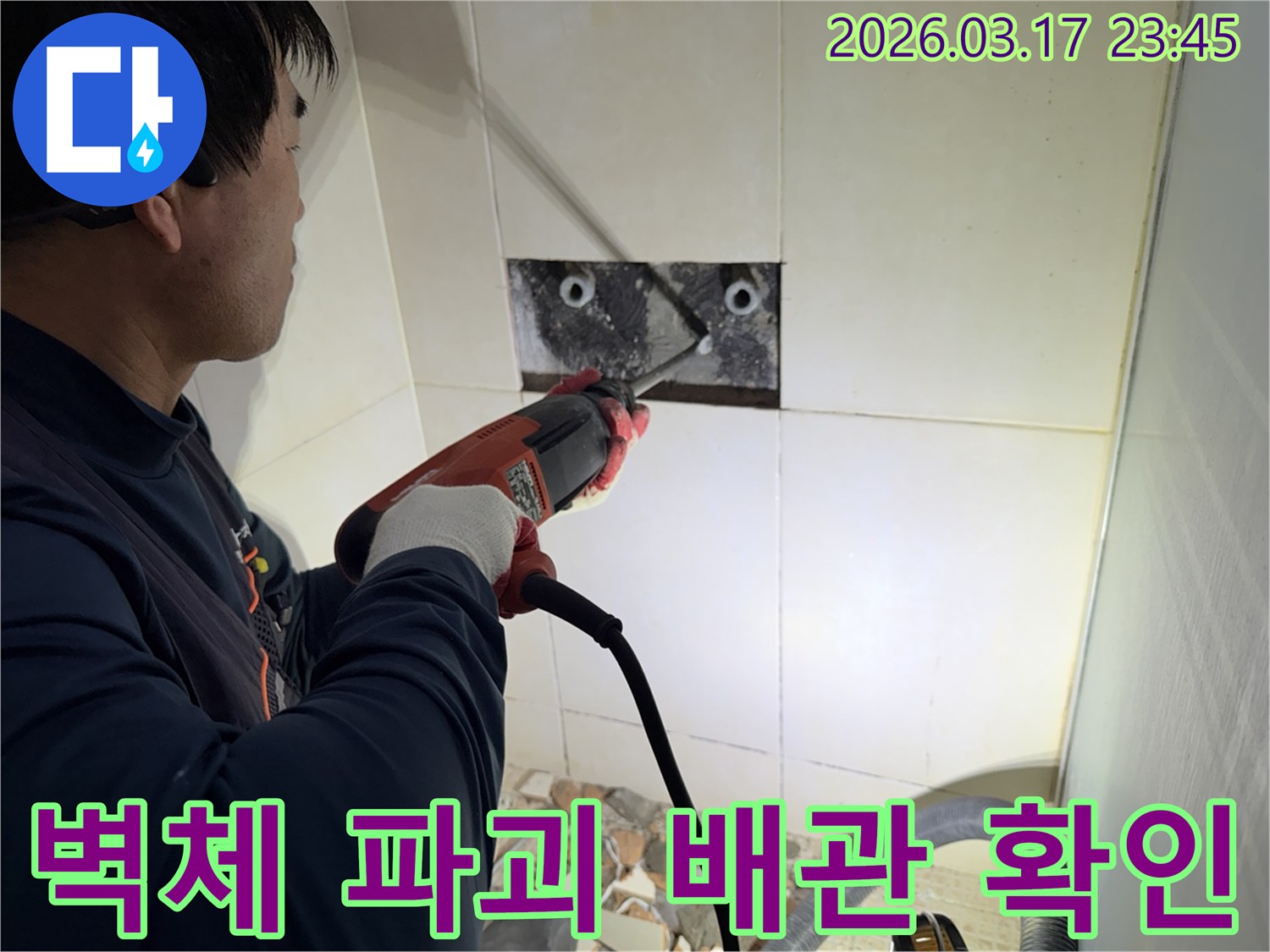 누수 공사 전문가가 벽면 타일을 조심스럽게 파쇄하여-누수 원인을 찾기 위한 배관 확인 작업을 진행하는 모습입니다.