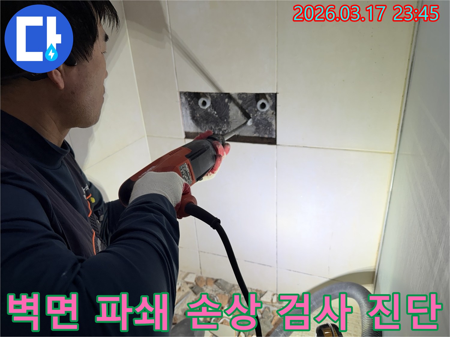 누수 전문가가 벽면 타일을 깨끗하게 파쇄하며-누수 원인인 배관의 손상 부위를 육안으로 검사하고 진단하는 작업을 진행 중입니다.